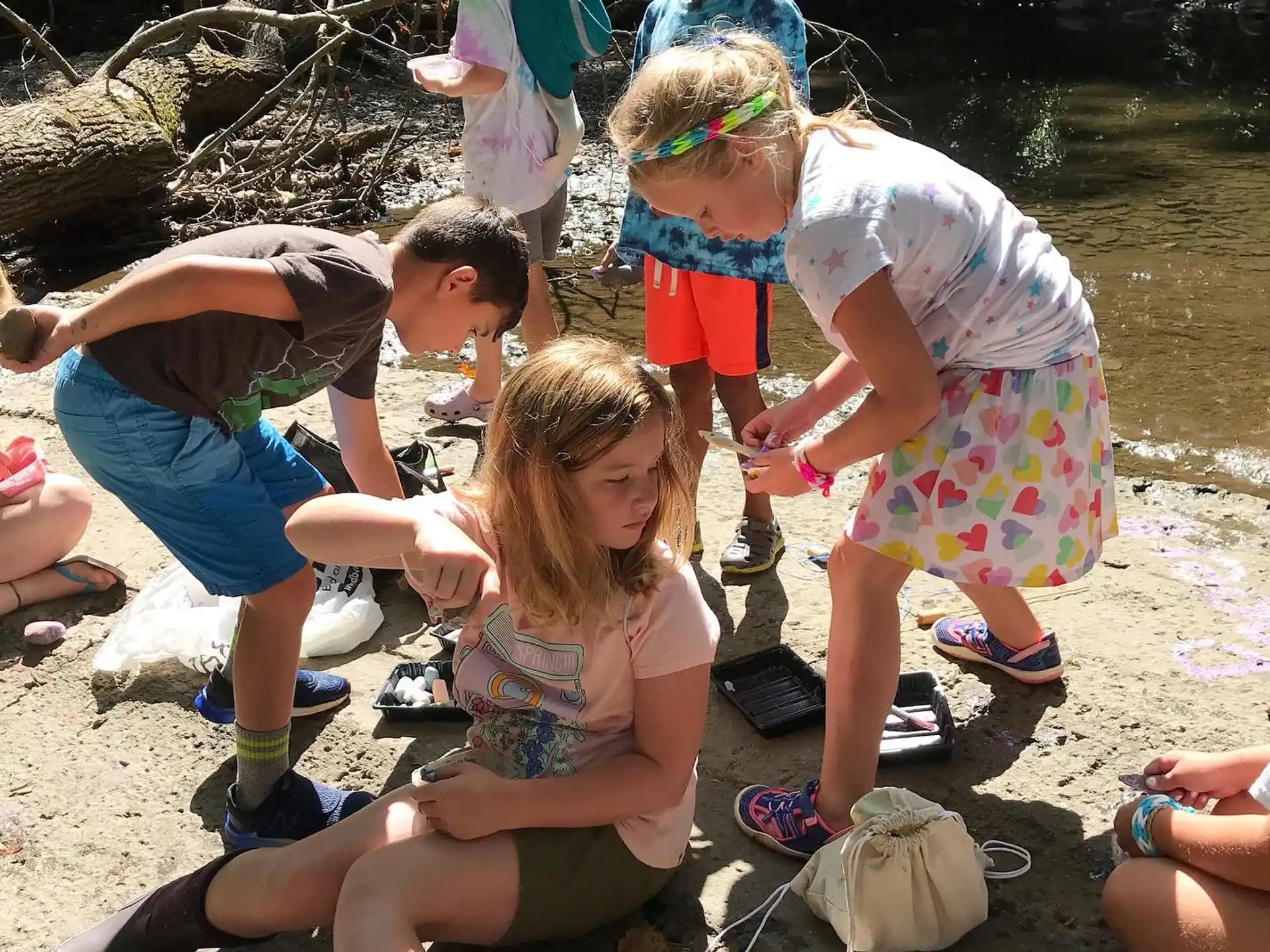 a group of people playing in the sand by a river