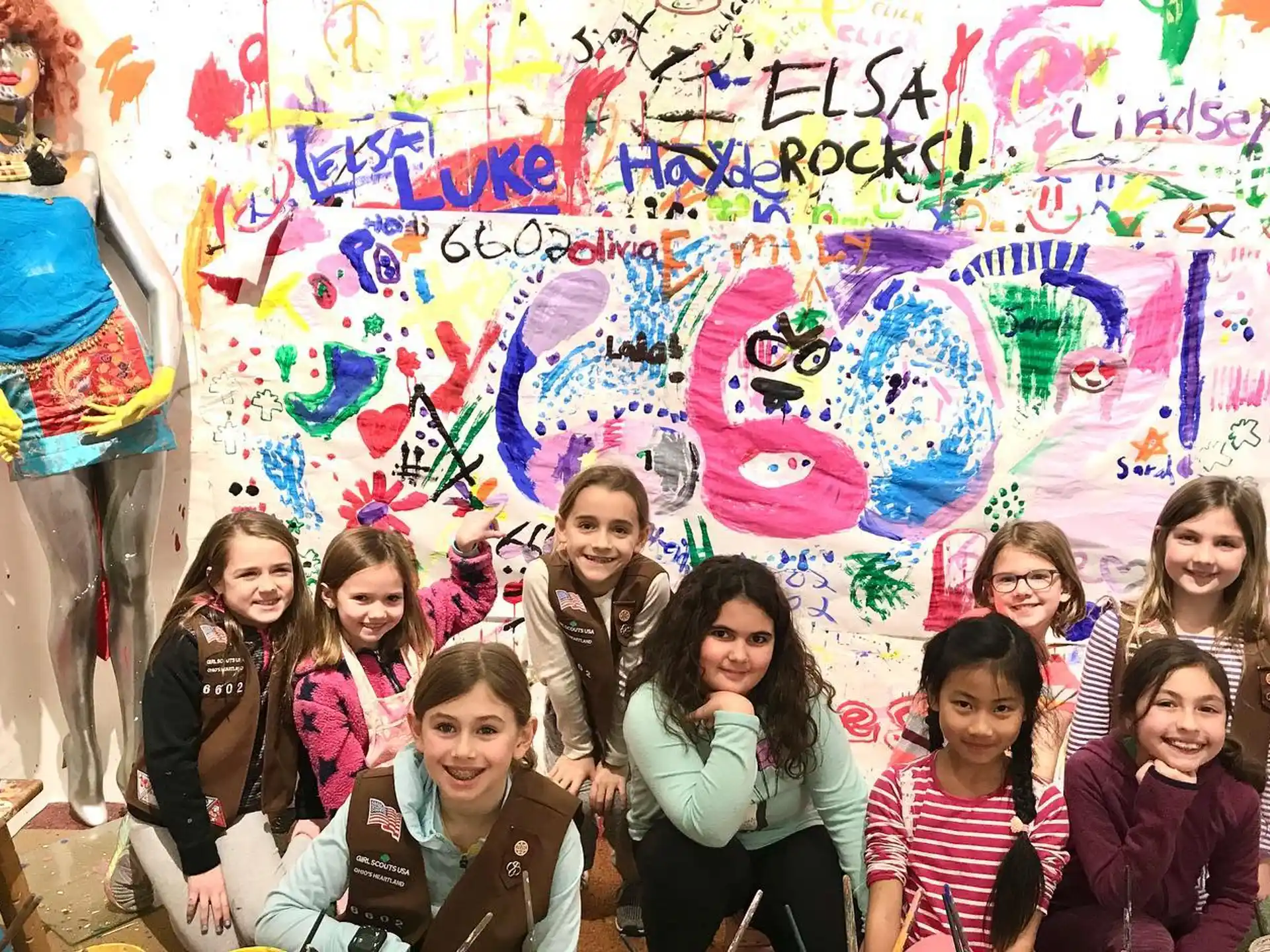 a group of people posing for a photo in front of a wall covered in graffiti