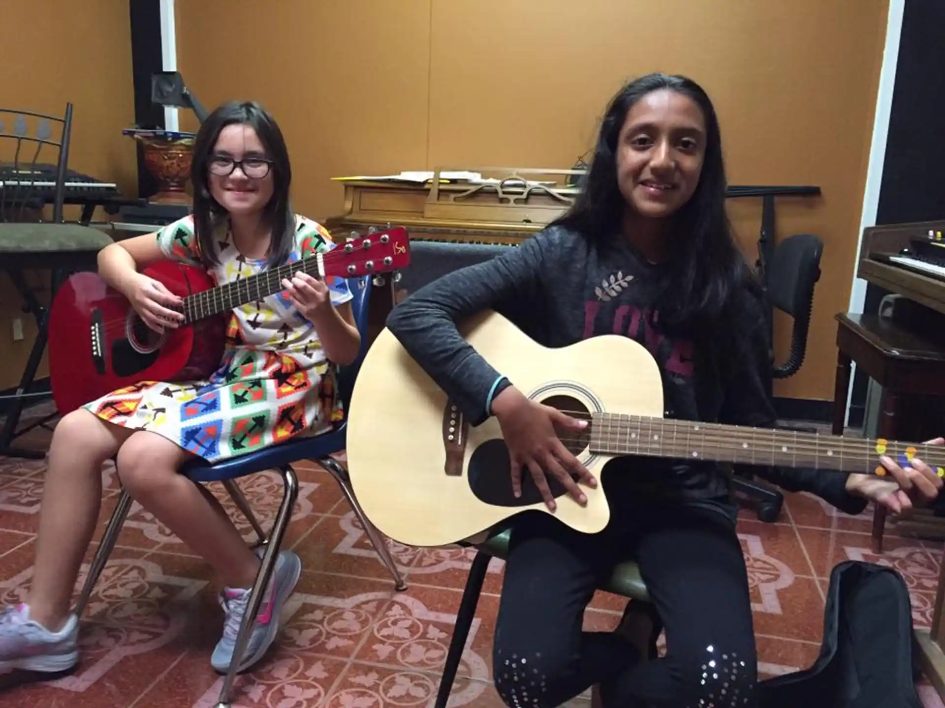 two women sitting in chairs holding guitars