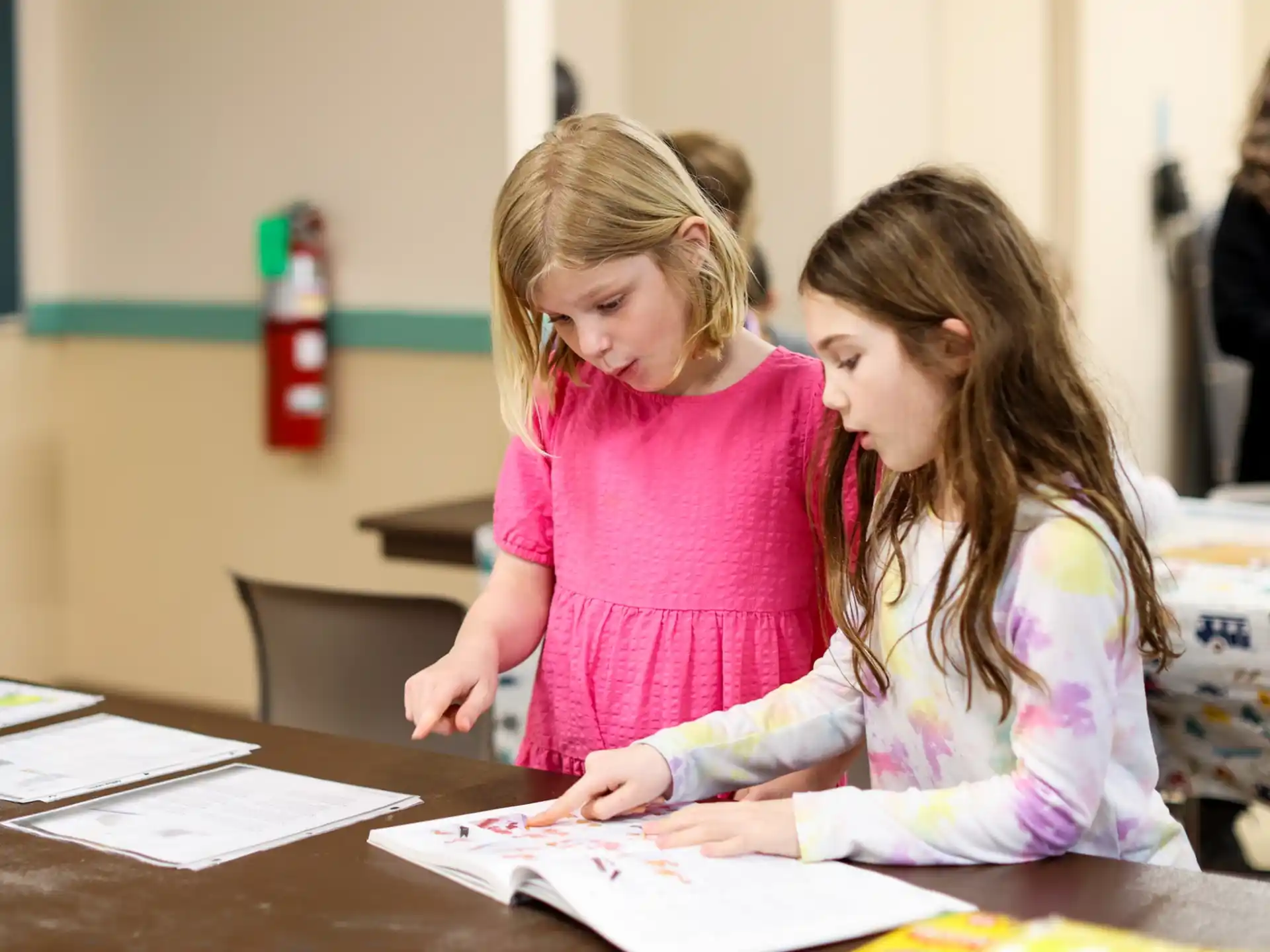 a couple of girls looking at a paper