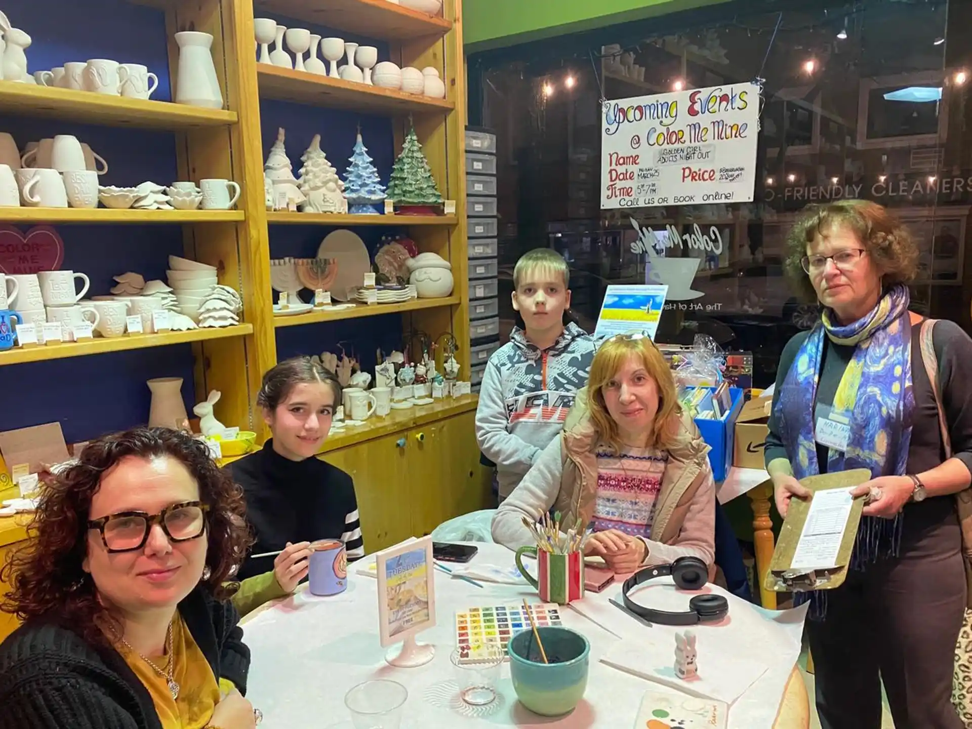 a group of people sitting at a table with a book and a sign