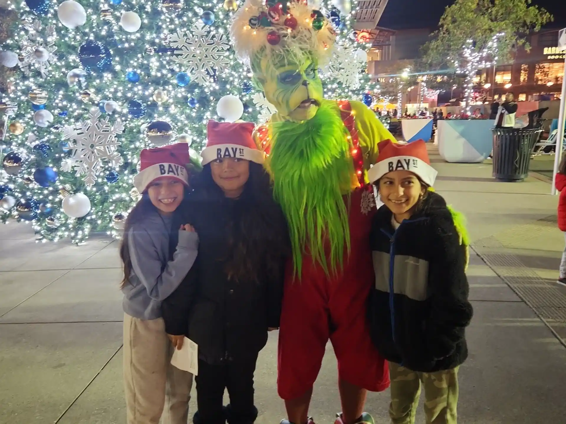 a group of people posing for a photo next to a large christmas tree