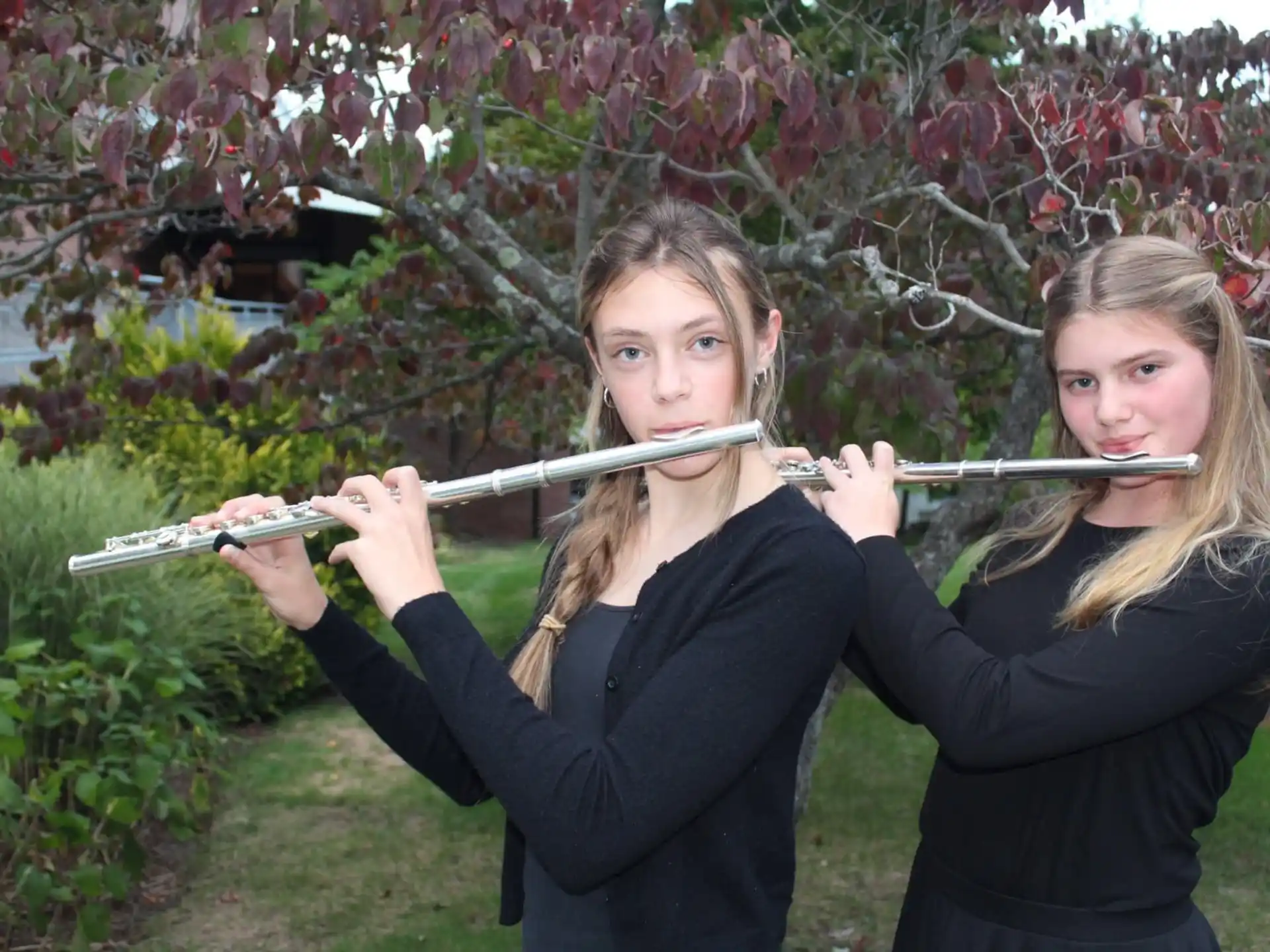 a couple of girls holding bows and arrows in front of a flowering tree
