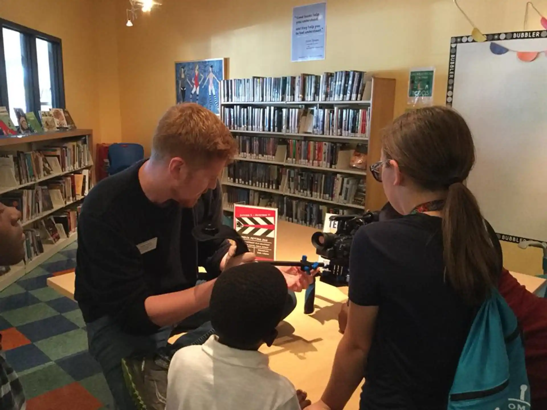 a man and woman looking at a child in a room with bookshelves