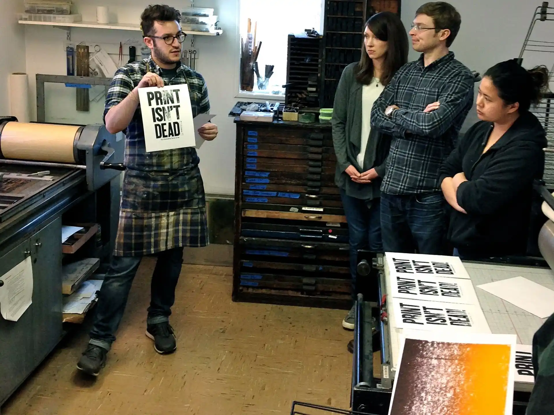 a group of people standing in a room with shelves and a table