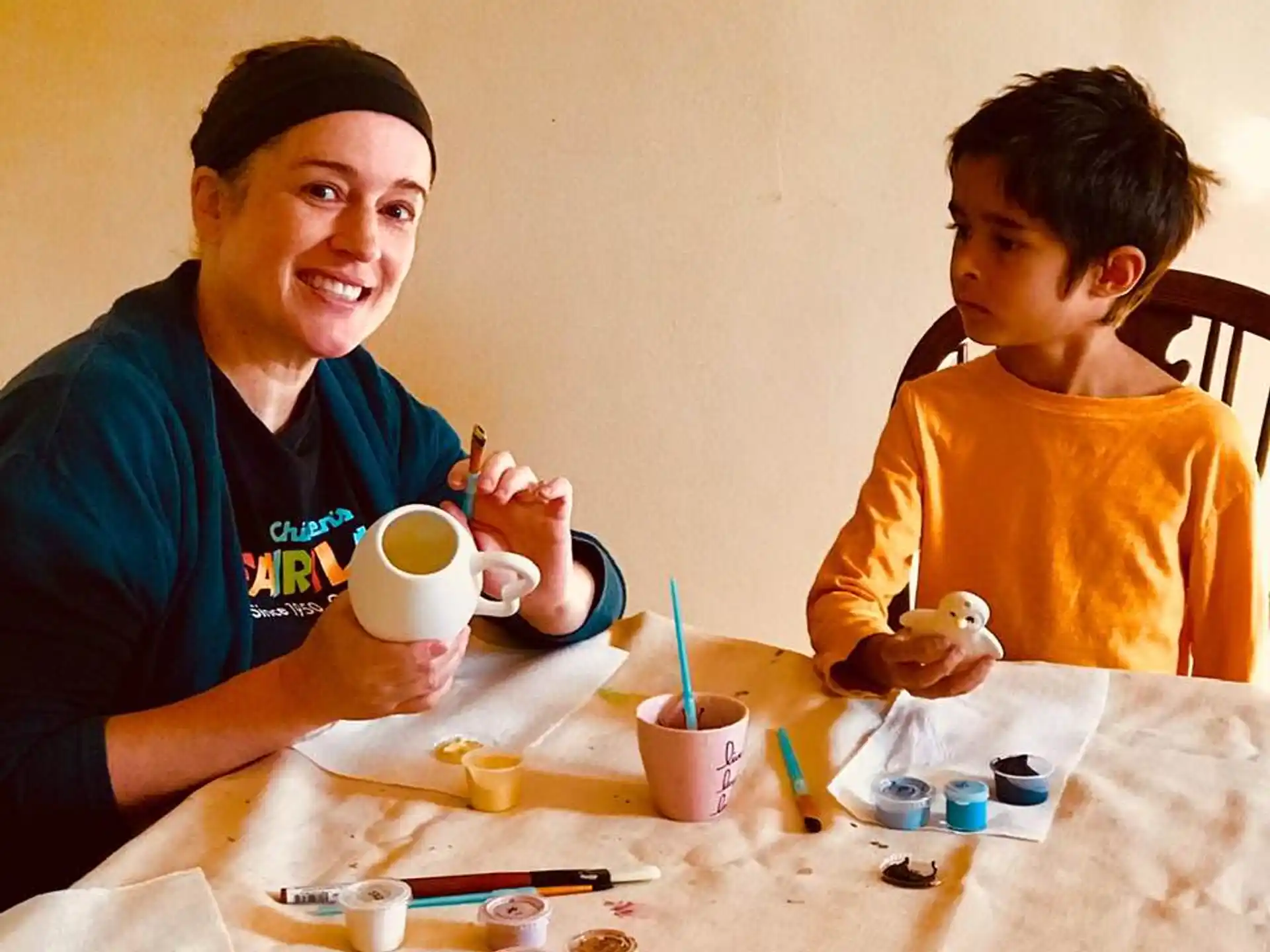 a person and a boy sitting at a table with cups and saucers