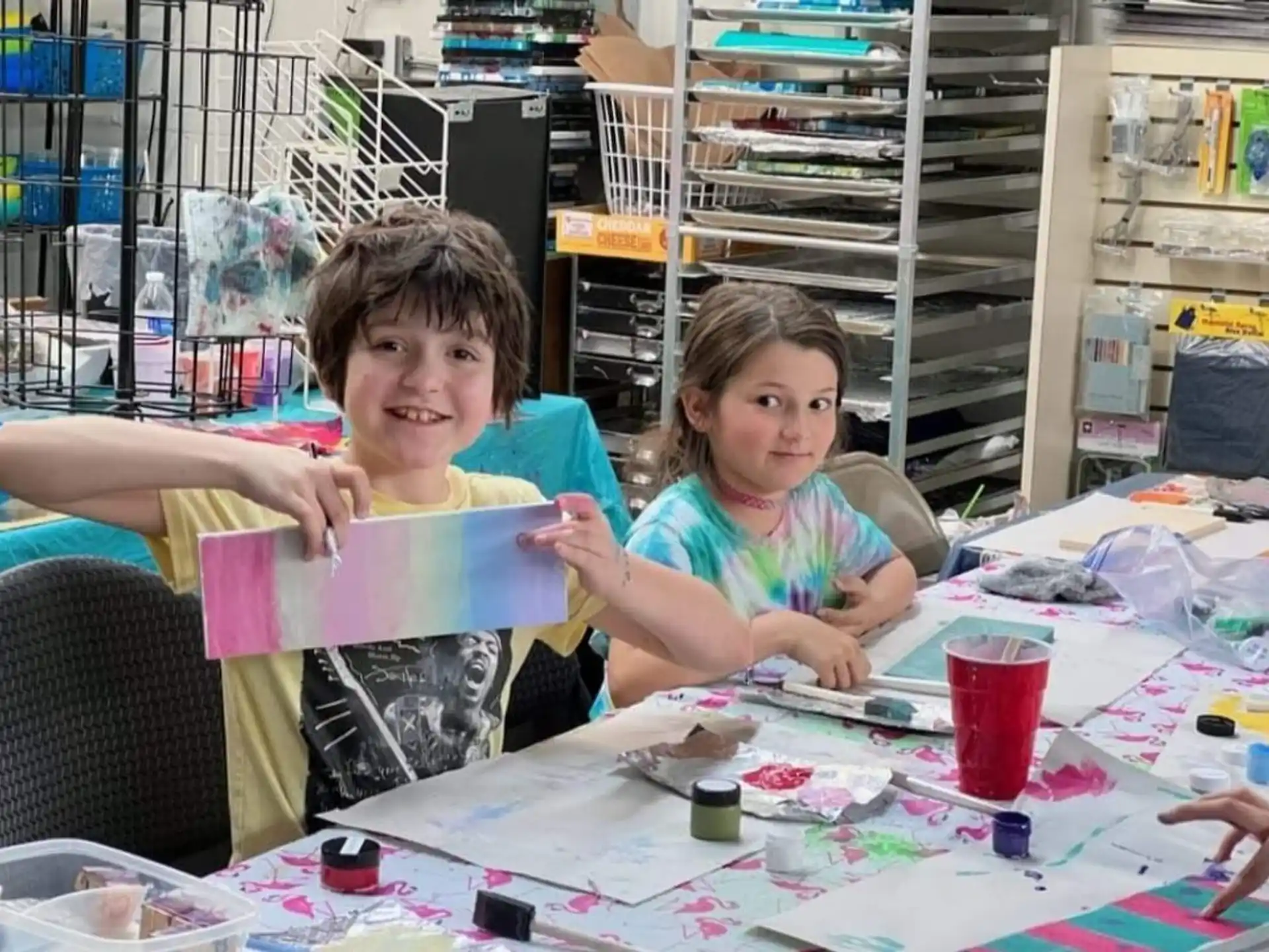 a couple of children sitting at a table with a drawing