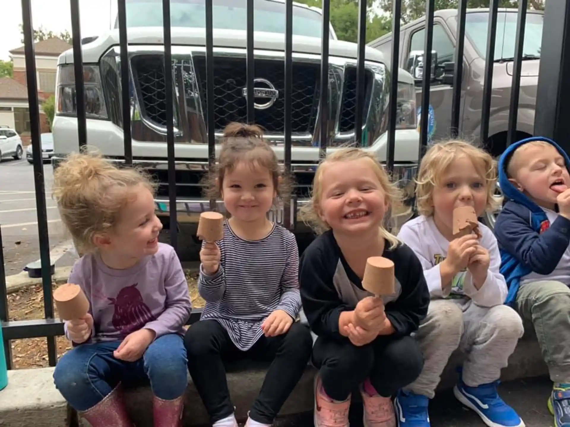 a group of children sitting on a bench eating ice cream