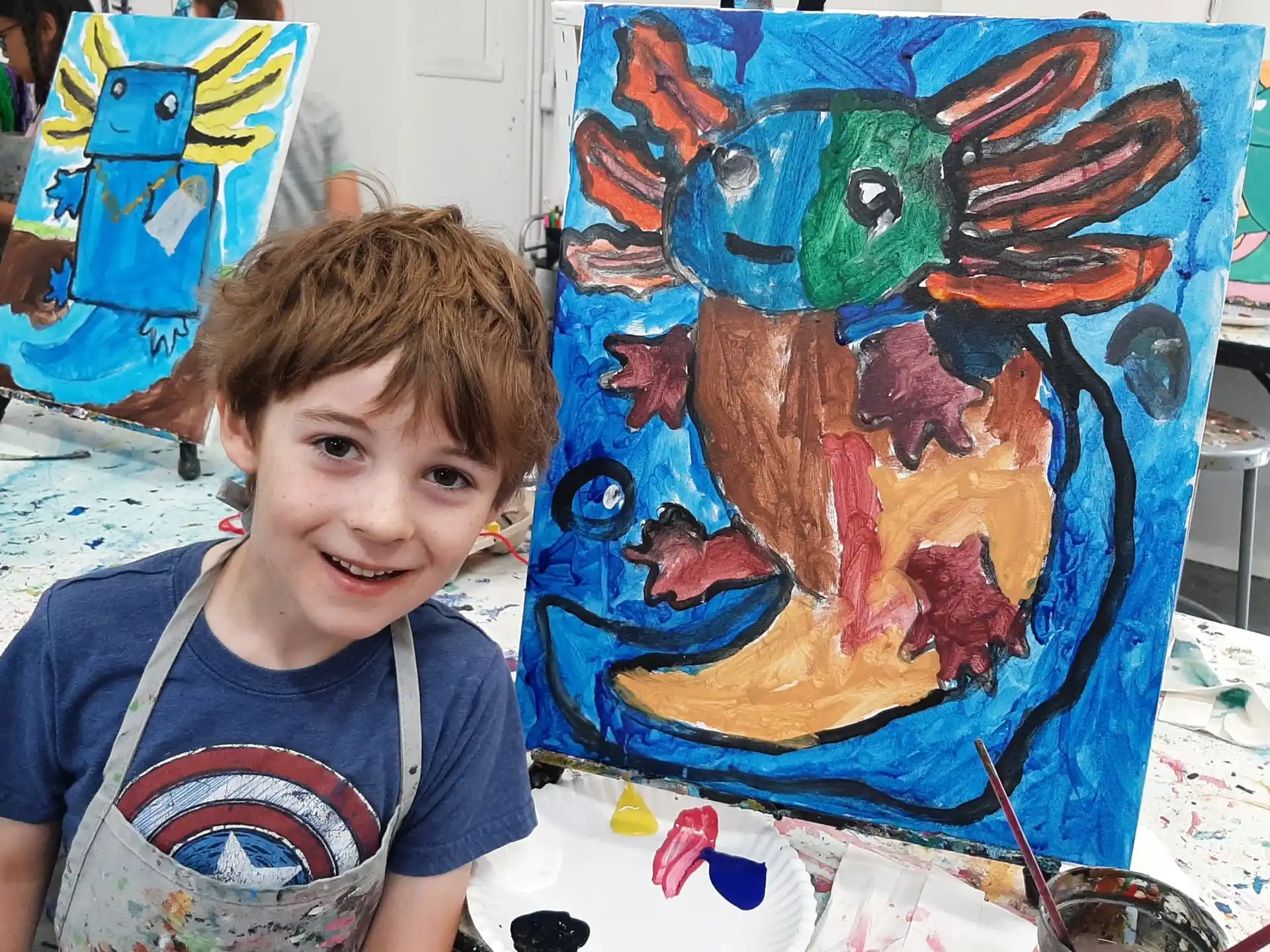 a boy sitting at a table with a painting on it