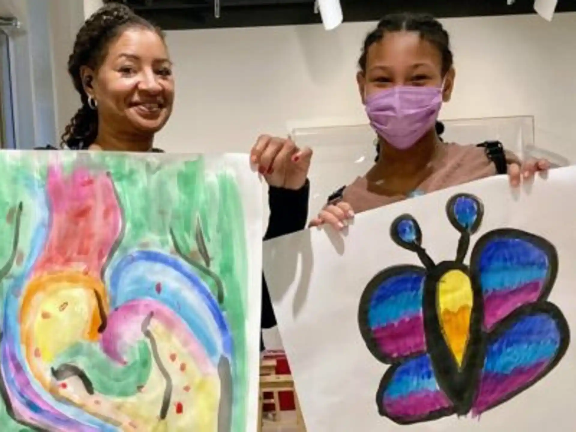 a couple of girls holding up artwork