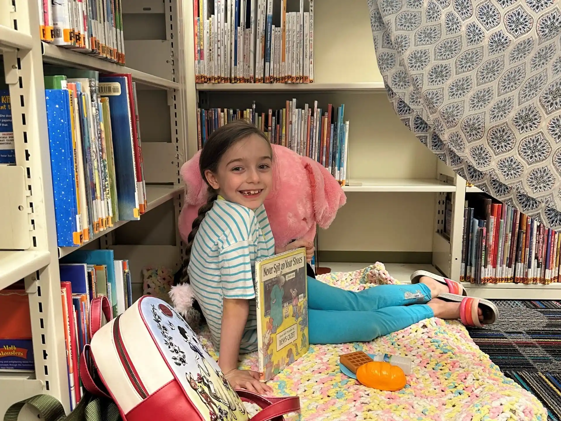 a couple of girls sitting at a table with books and a book