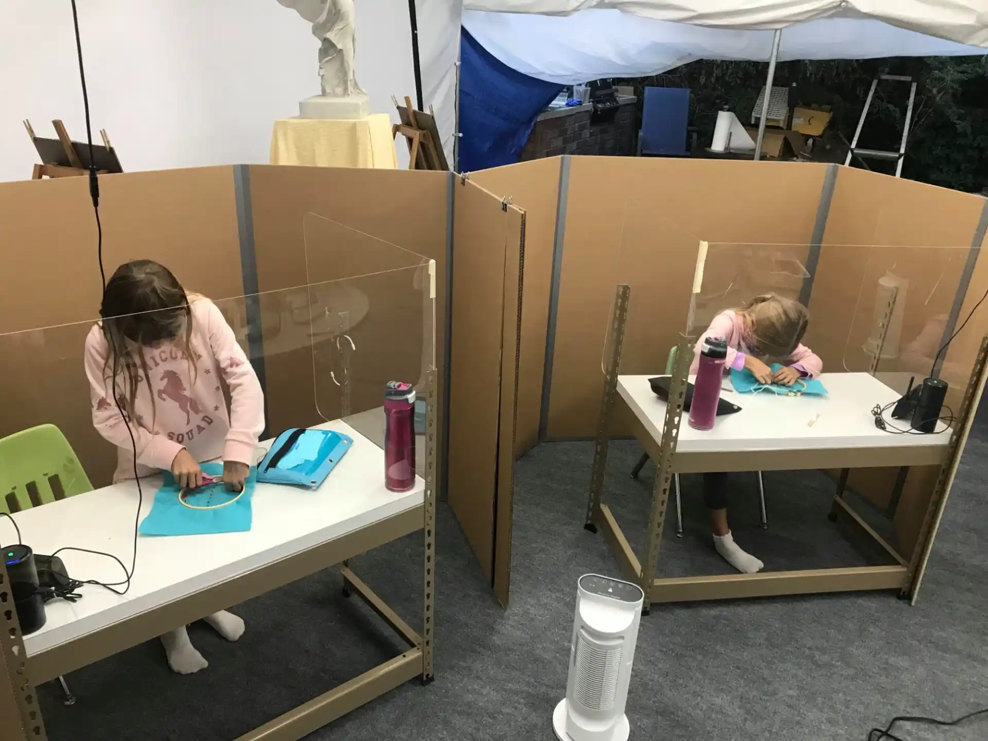 a couple of girls sitting at a table with a phone and a bottle of water