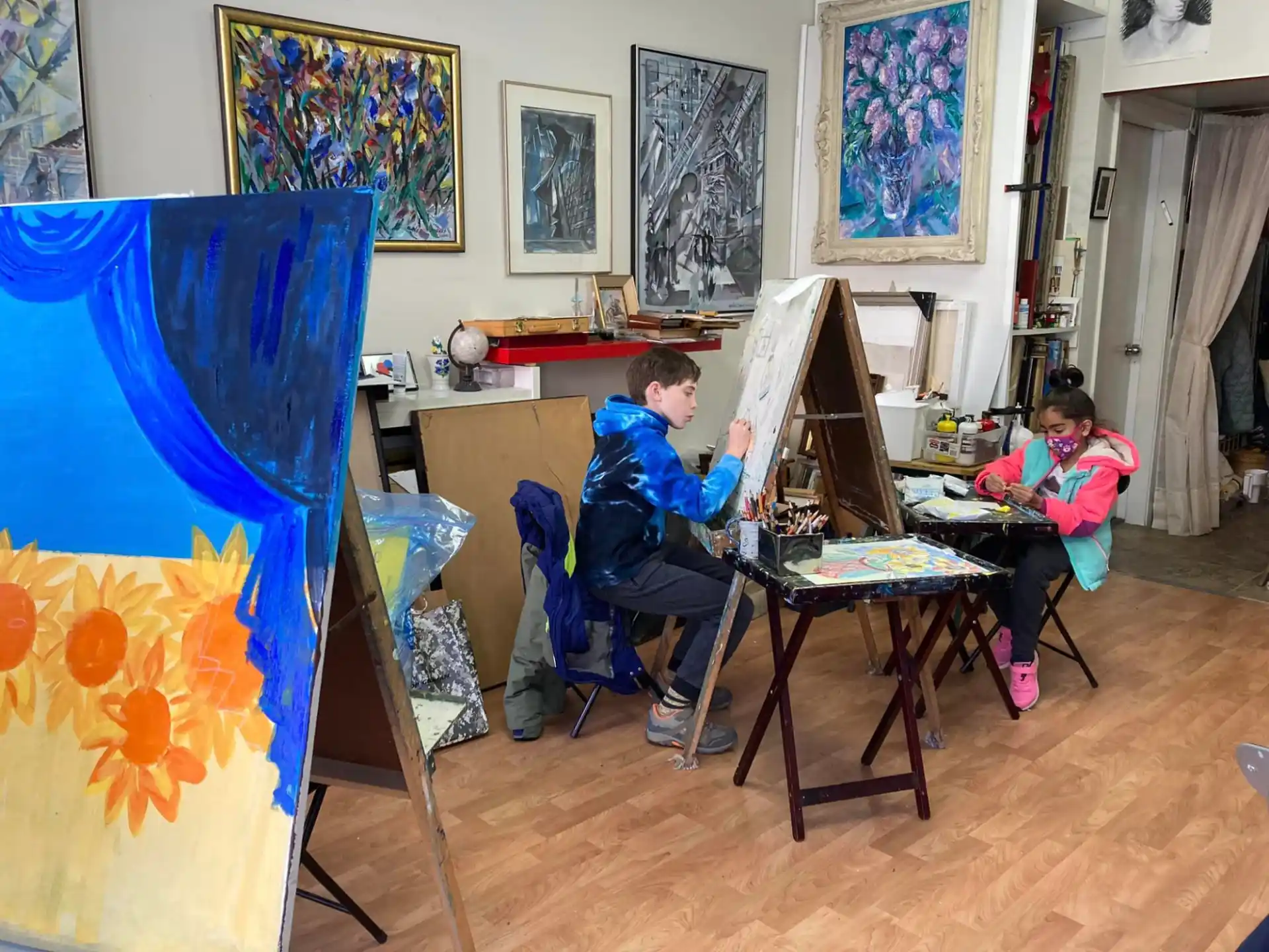 children sitting at desks in a room with art on the wall