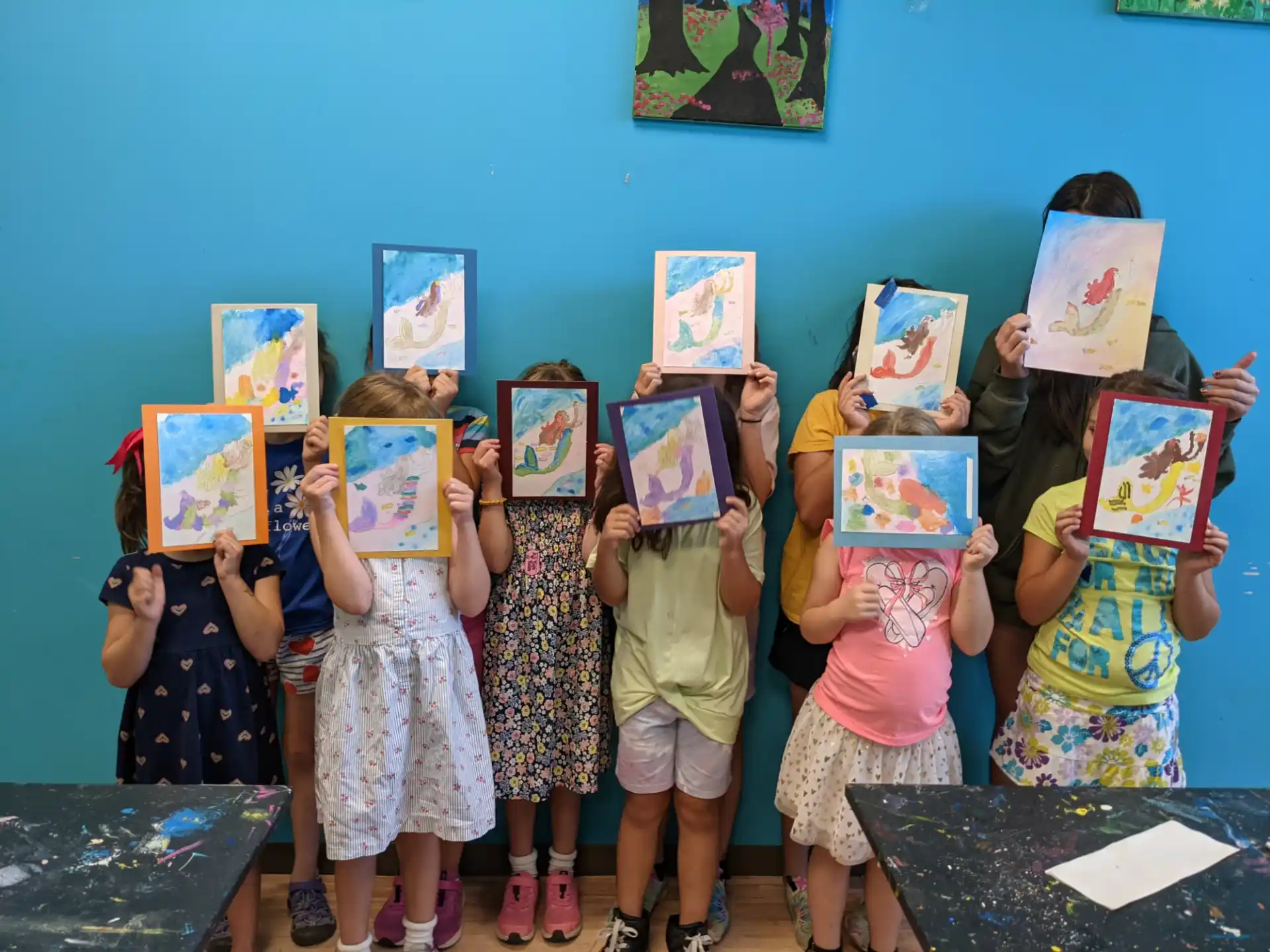 a group of children holding up framed pictures