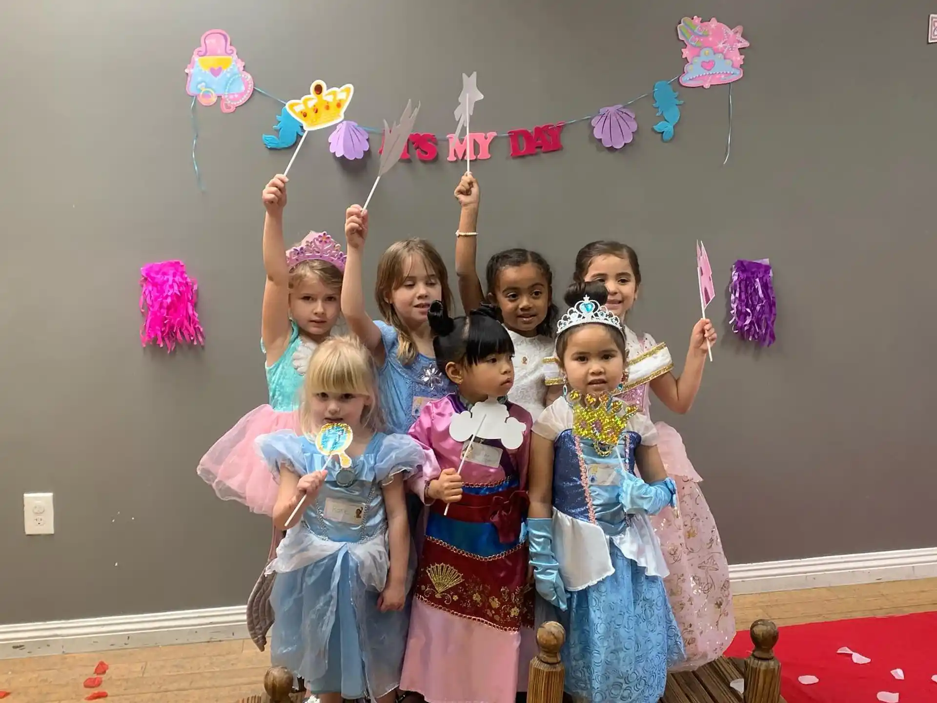 a group of girls holding up colorful balloons