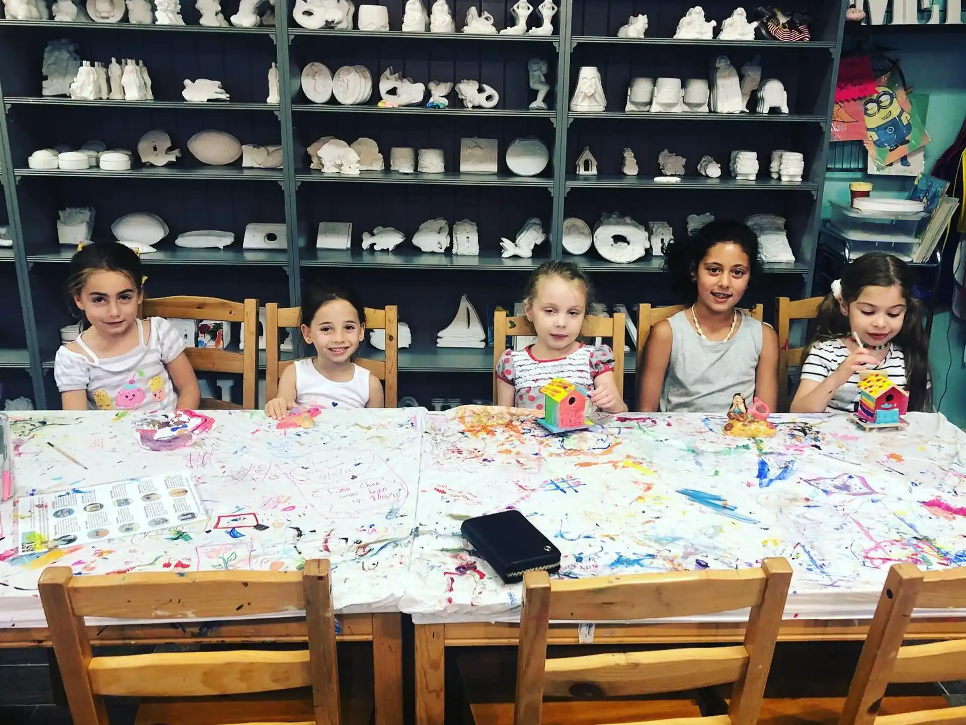 a group of children sitting at a table in a room with shelves