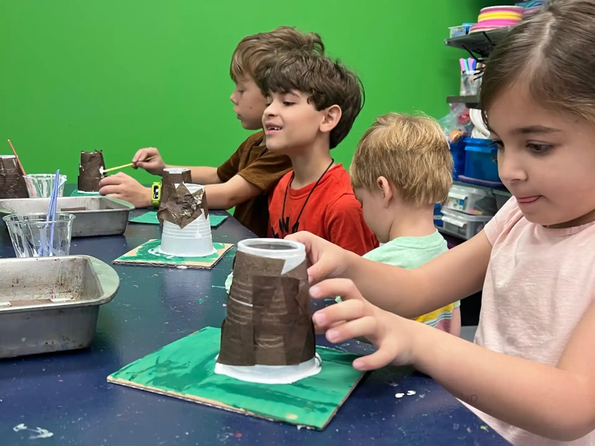 a group of kids sitting at a table with a cake