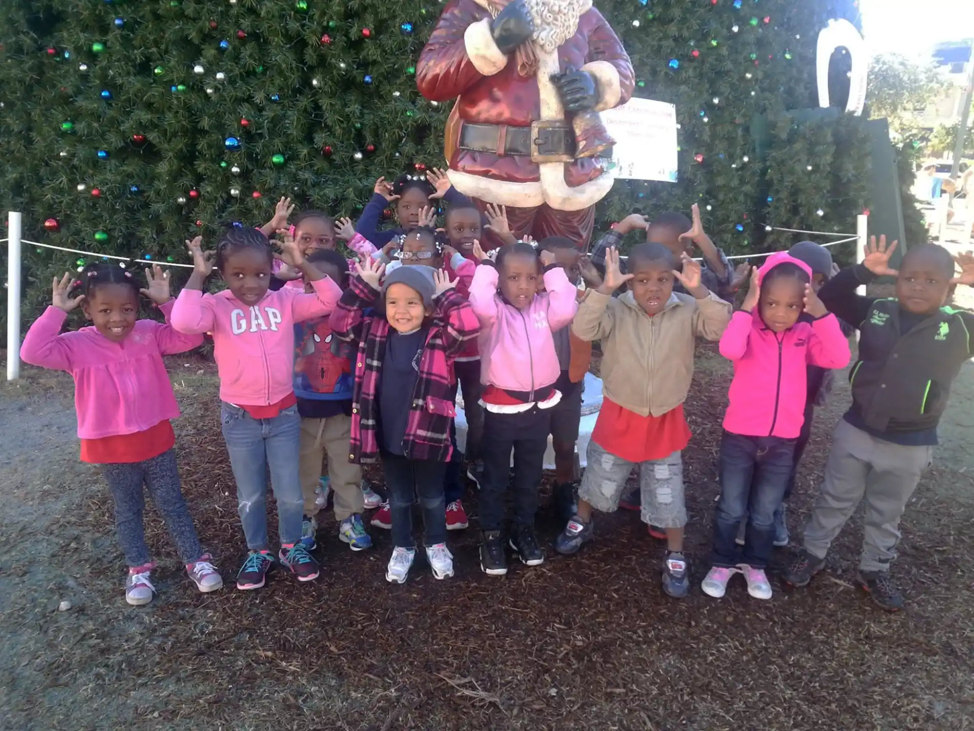 a group of children posing for a photo in front of a christmas tree