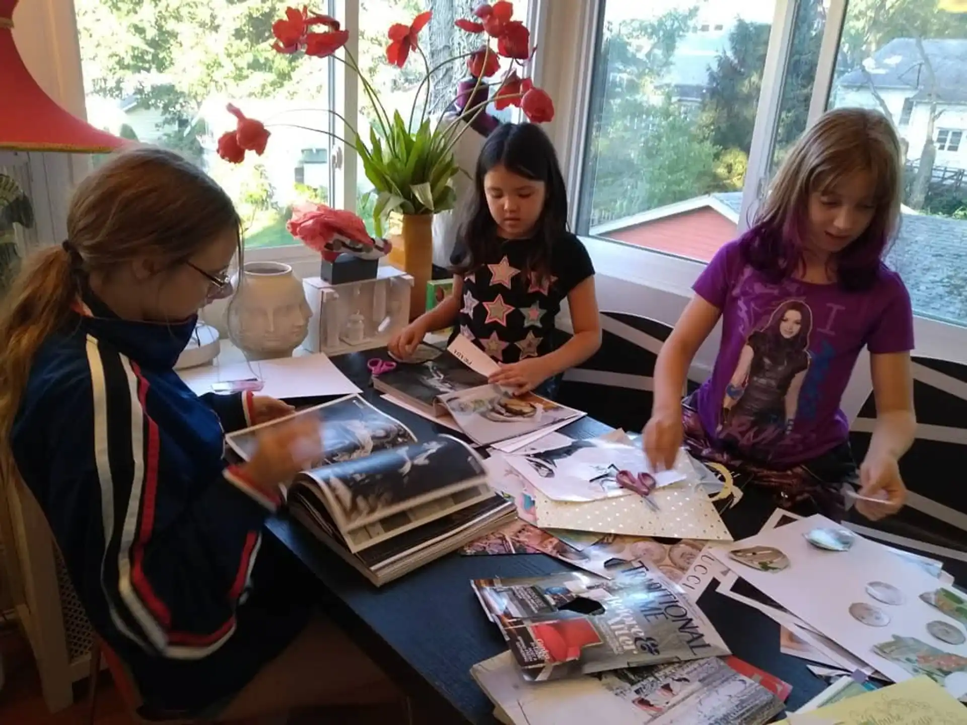 a group of girls sitting at a table with books and flowers
