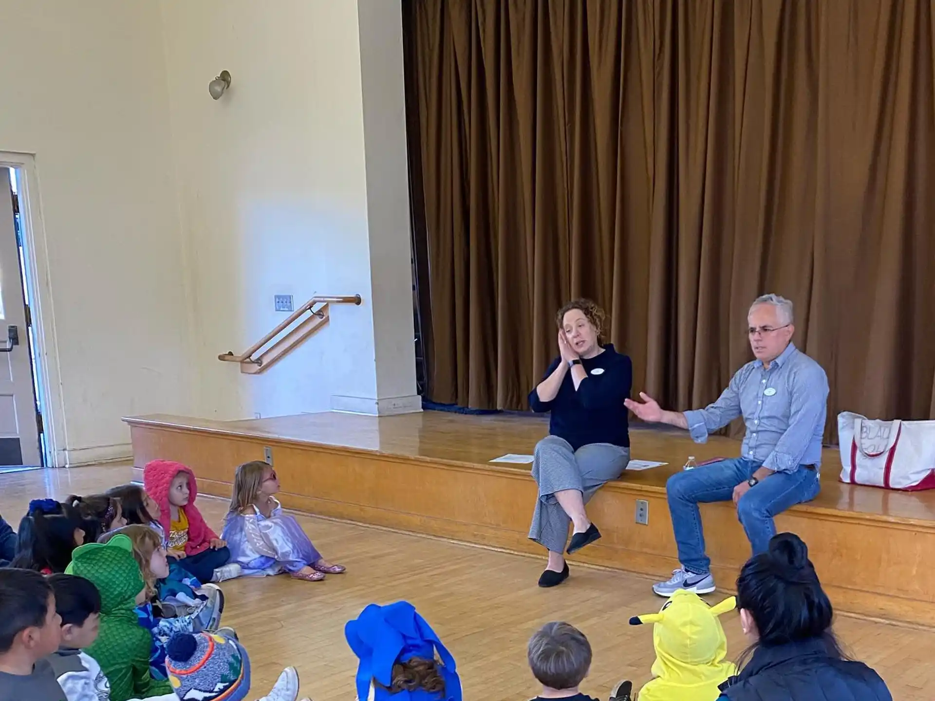 a man and woman sitting on the floor with a group of children