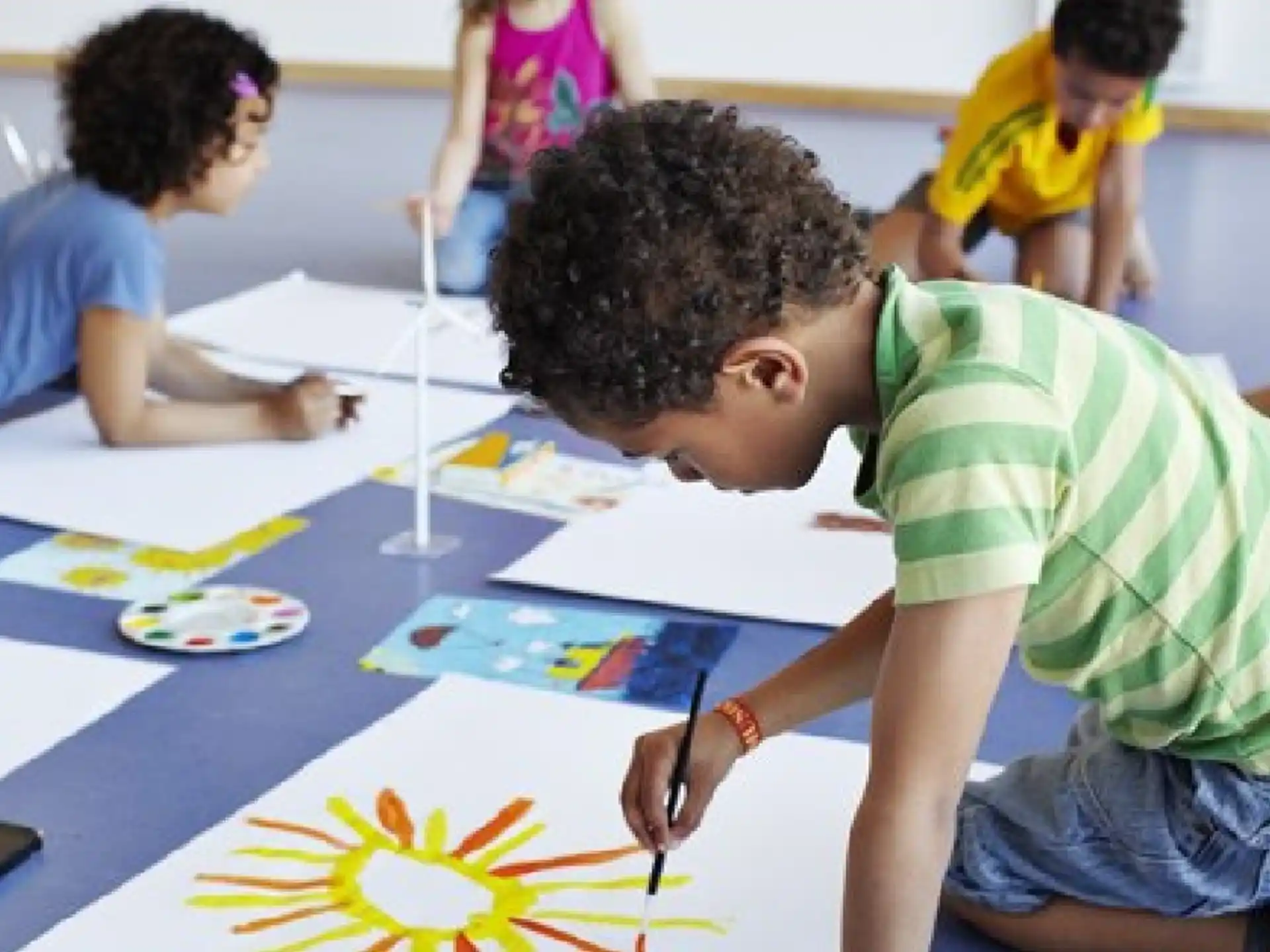 a group of people sitting around a table painting