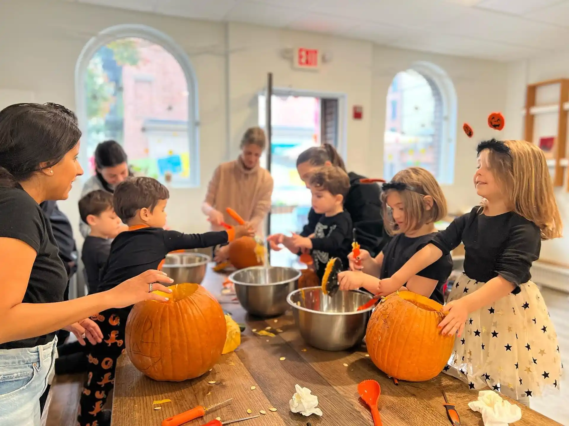 a group of people around a table with pumpkins