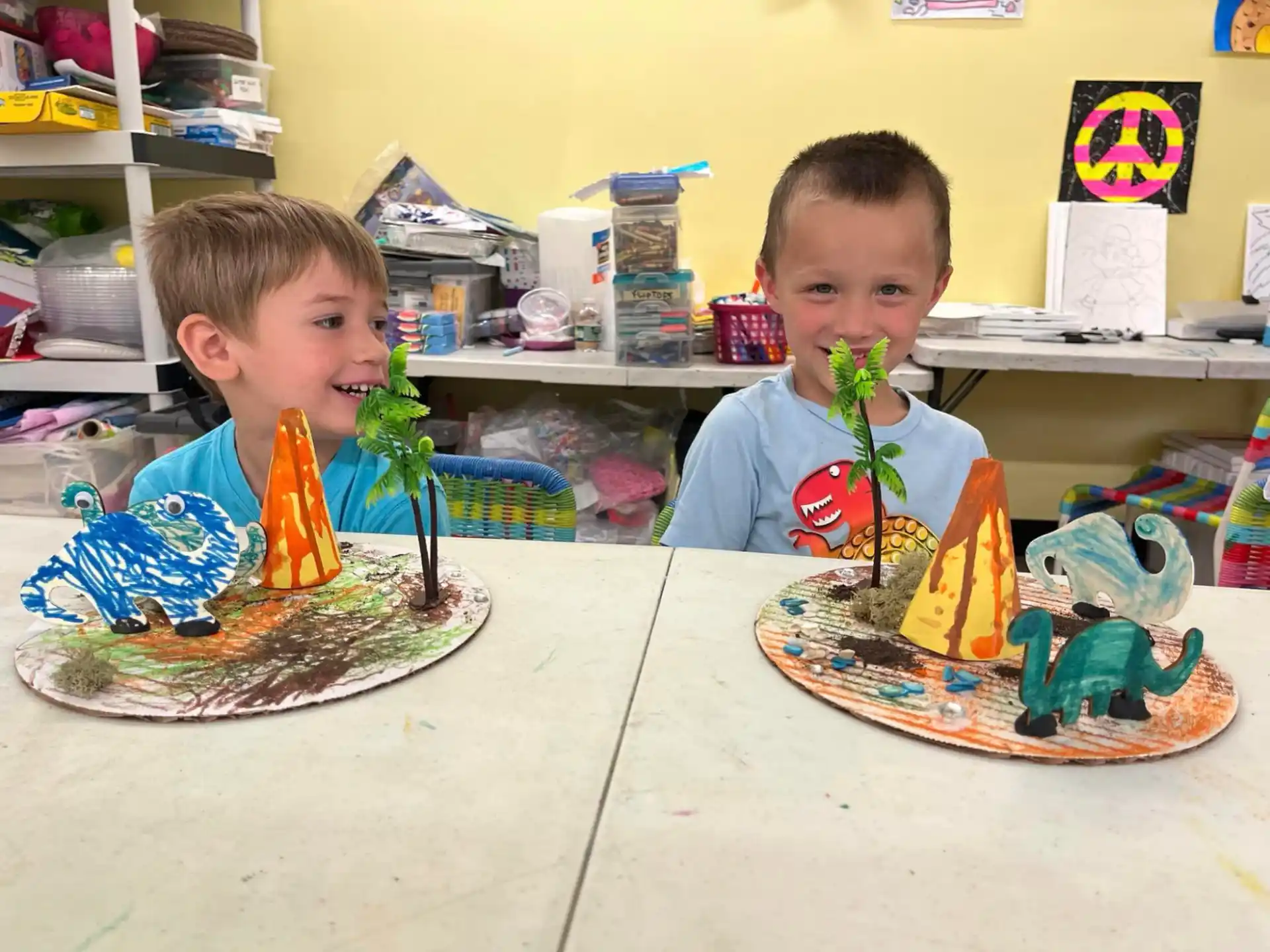 two boys sitting at a table with a cake and a toy train