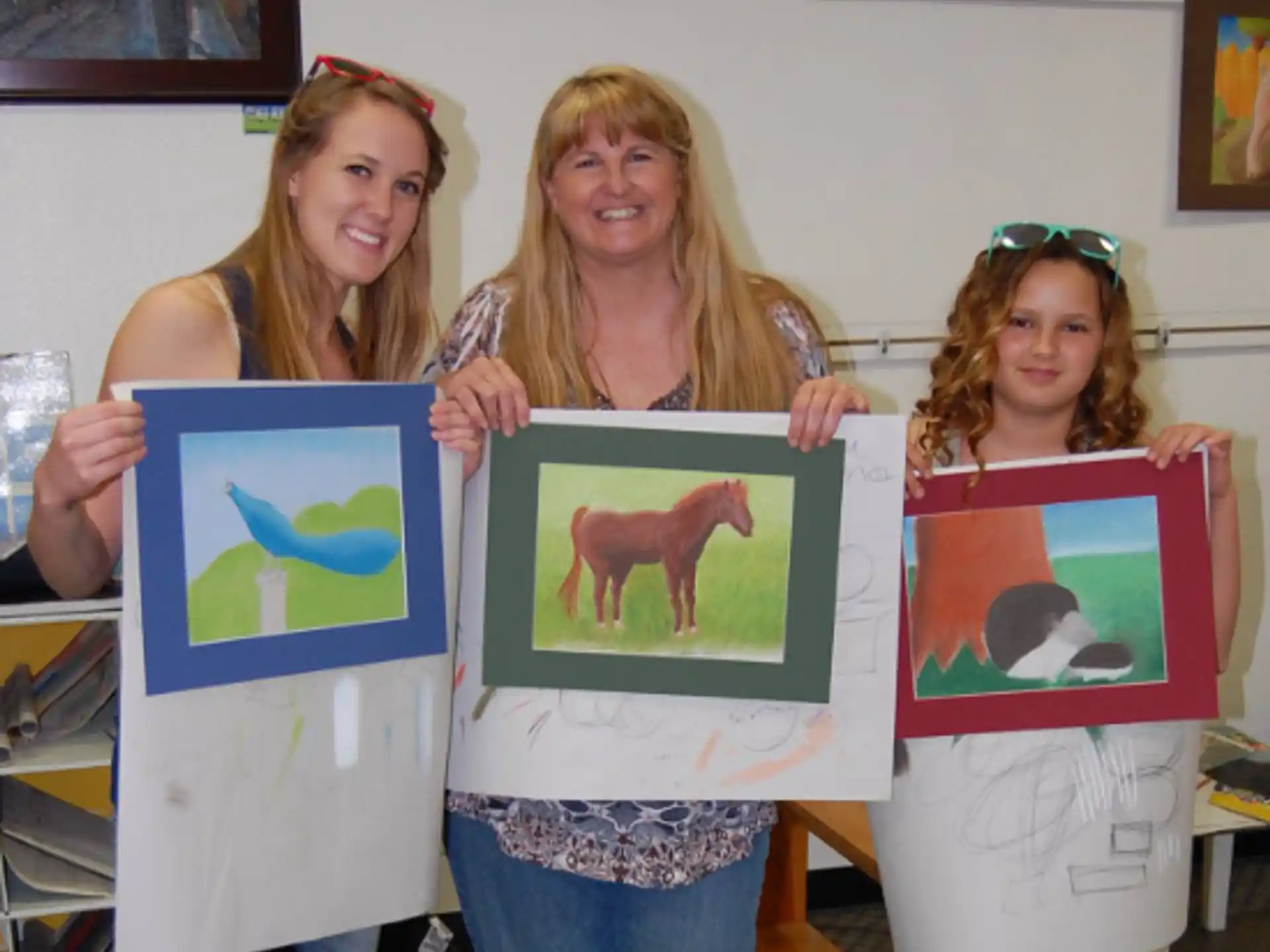 a group of women holding up framed pictures