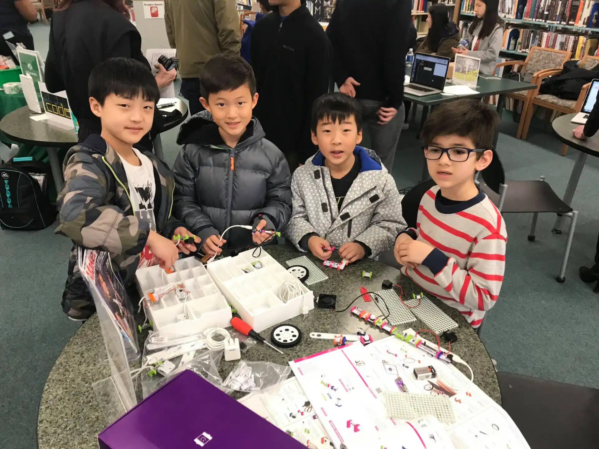 a group of boys sitting at a table with a board game