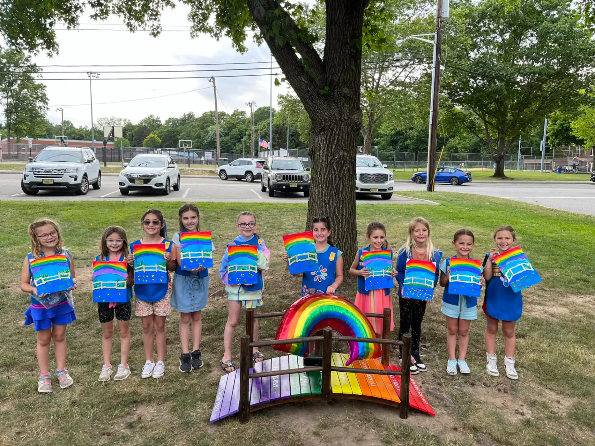 a group of children standing next to a tree and a playground