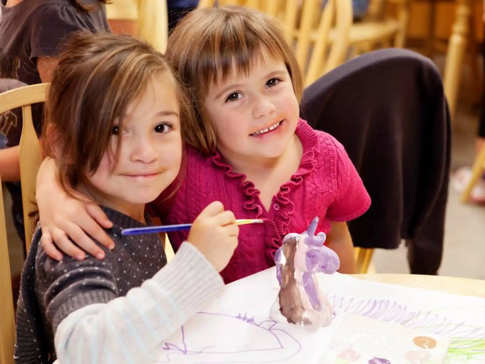 a couple of girls sitting at a table with a cupcake