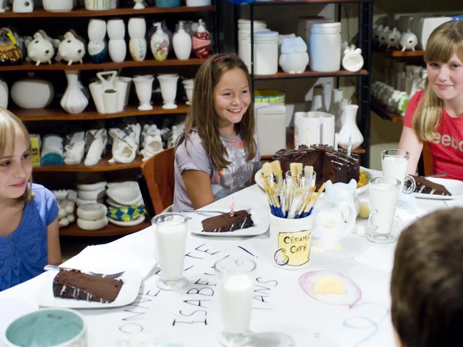 a group of children sitting at a table with a cake