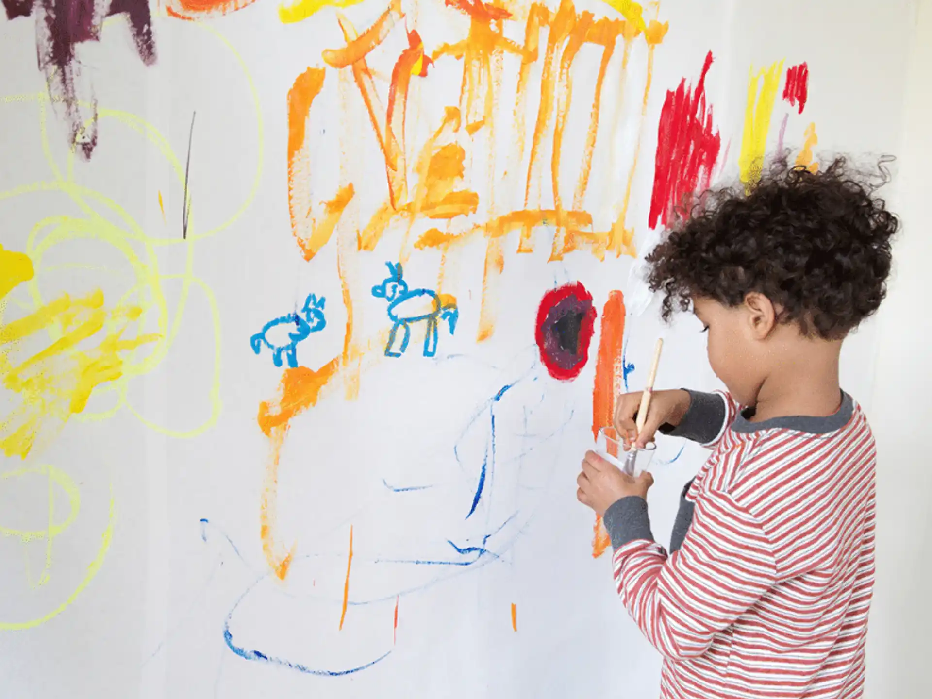 a young boy painting on a wall