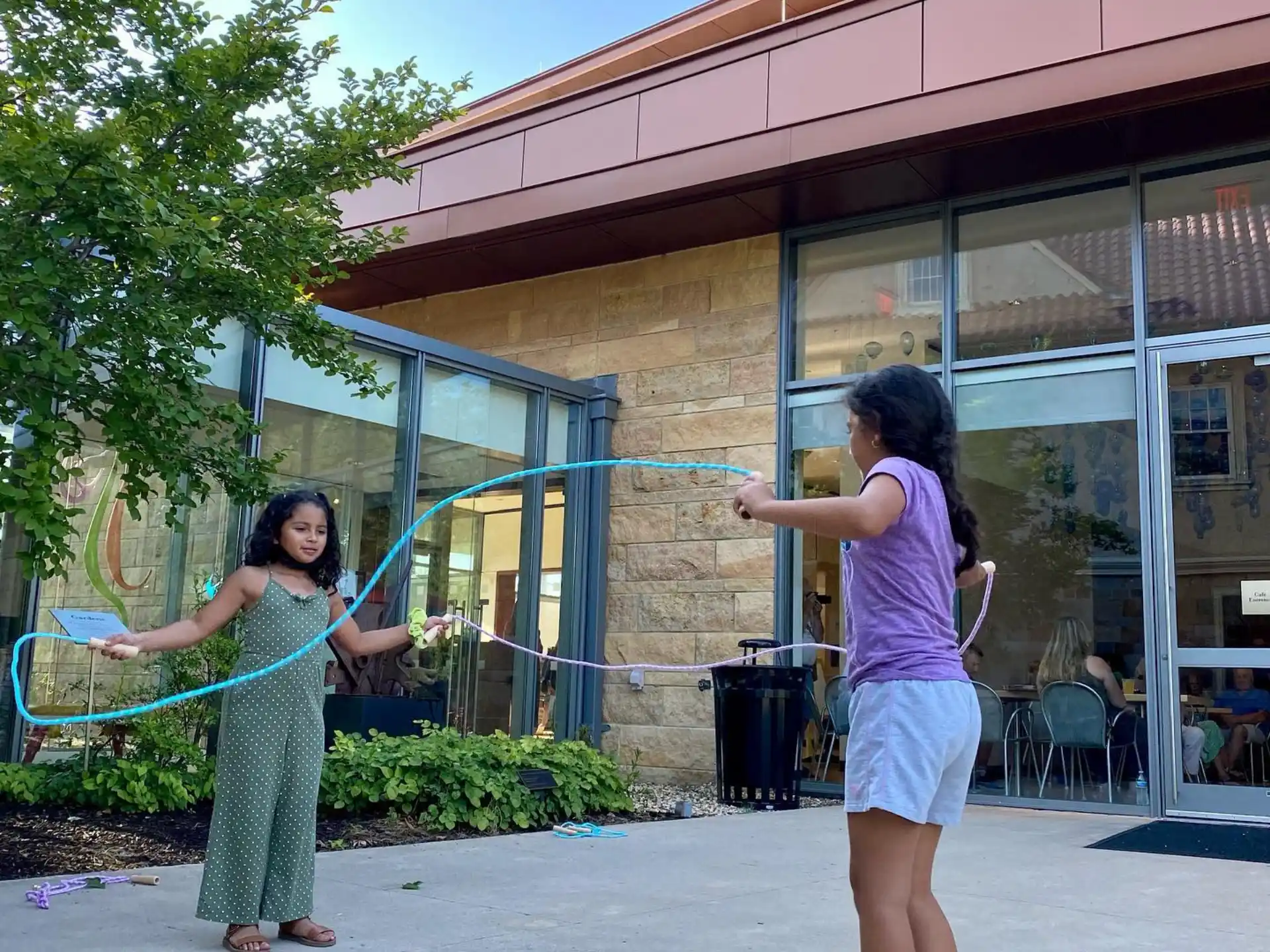 a couple of women playing with a frisbee outside a building