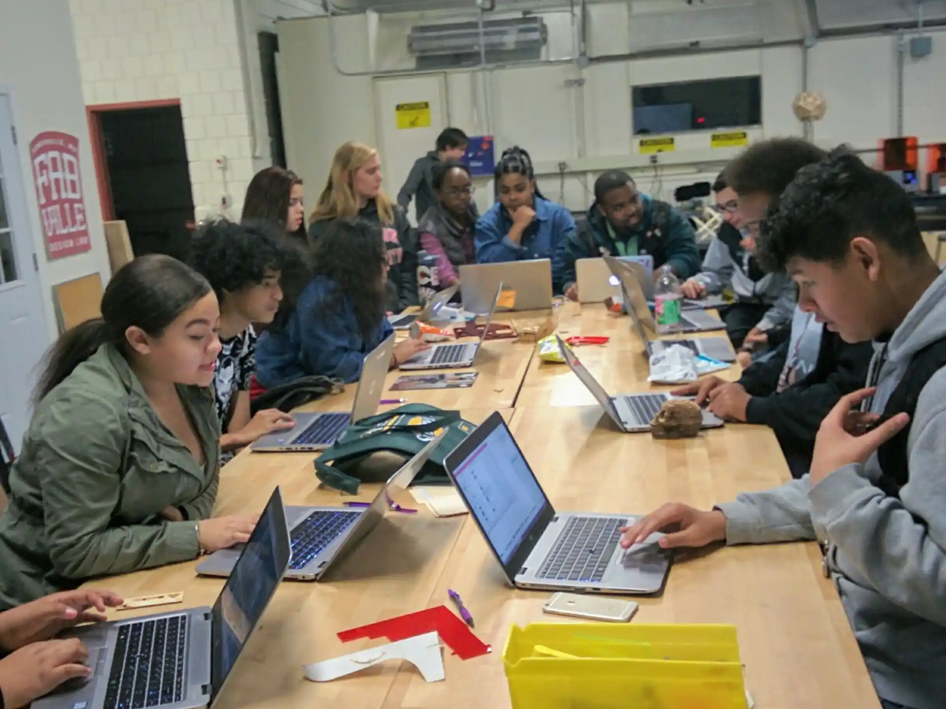 a group of people sitting at a table with laptops