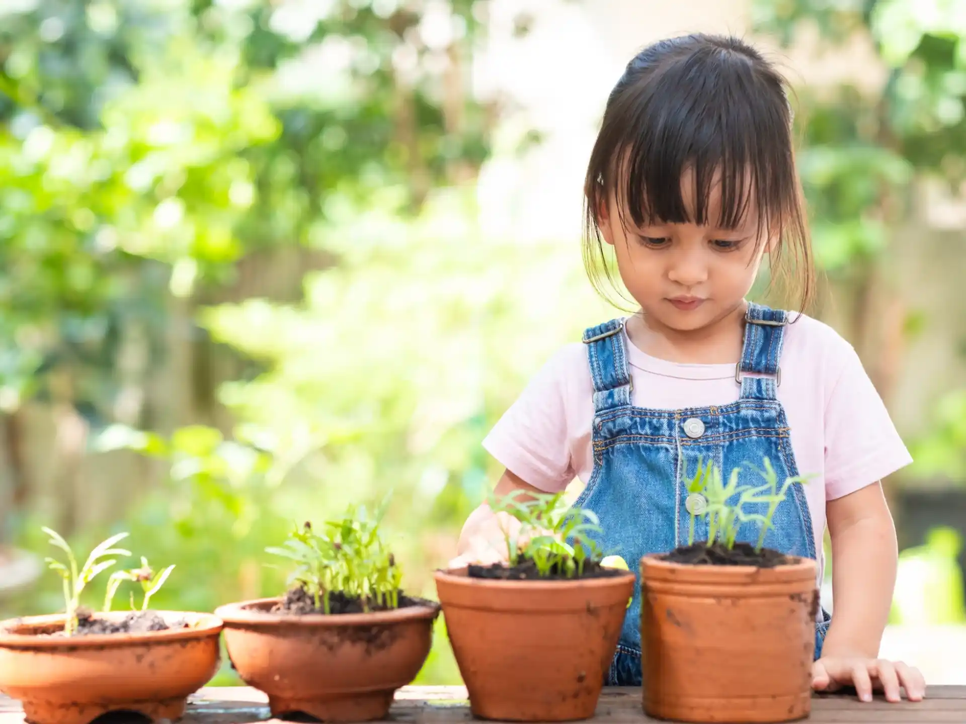 a child standing next to potted plants