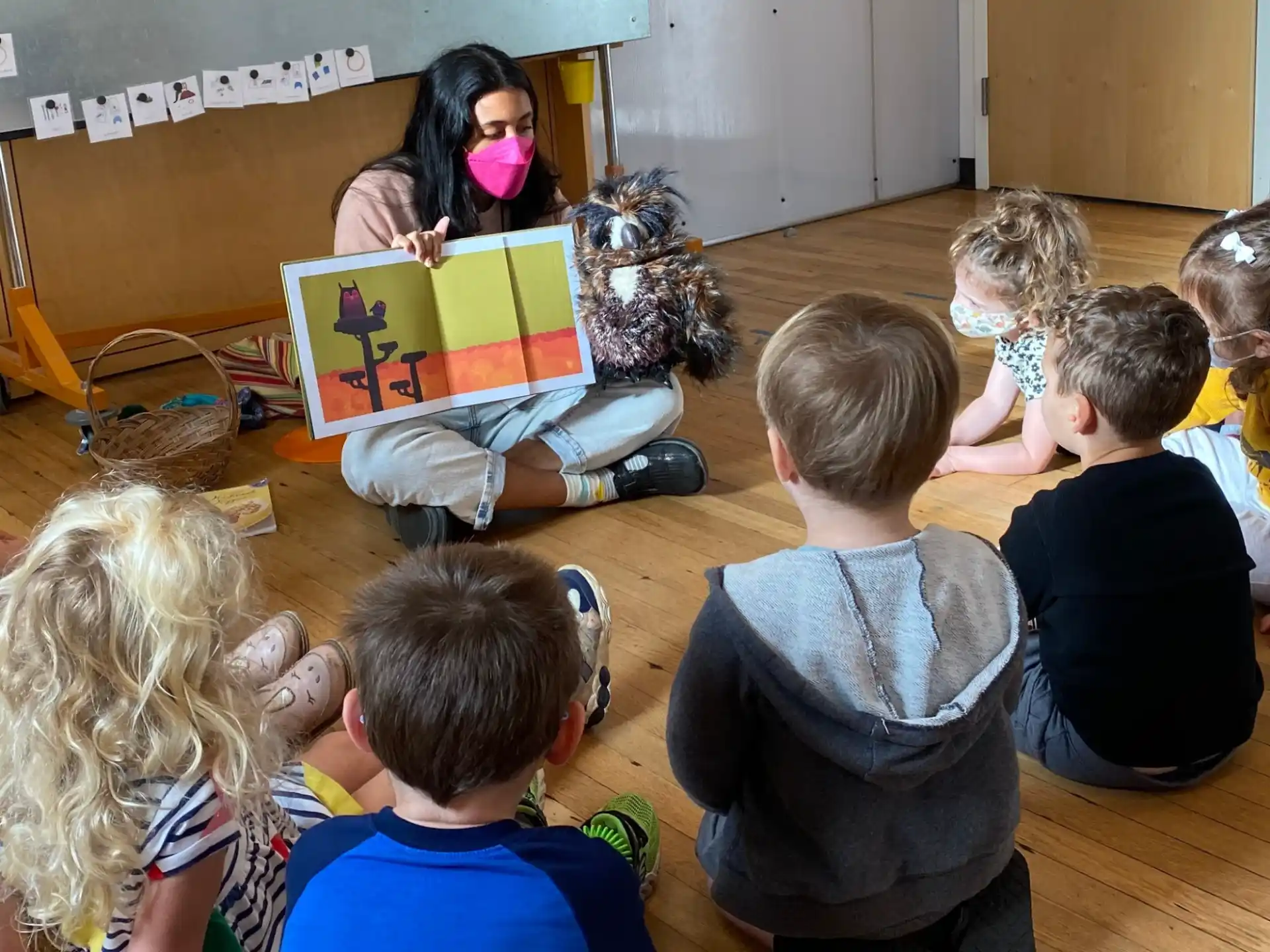 a group of children sitting on the floor looking at a laptop