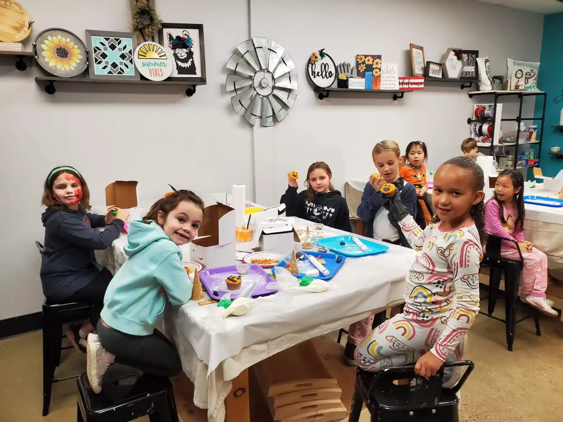 a group of children sitting around a table with a white tablecloth