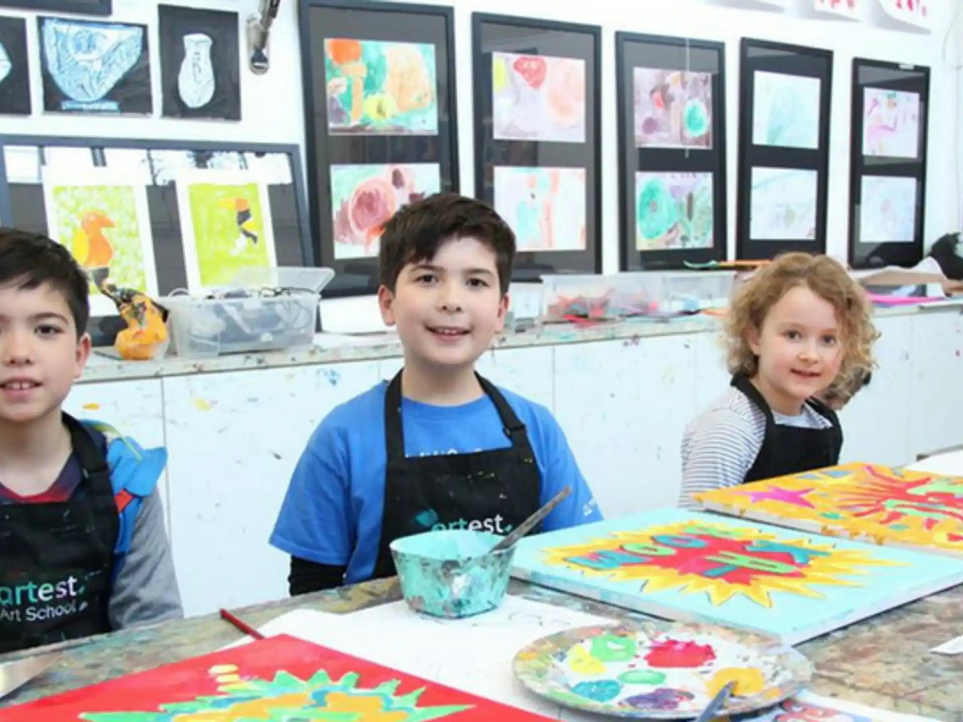 a group of kids sitting at a table with food