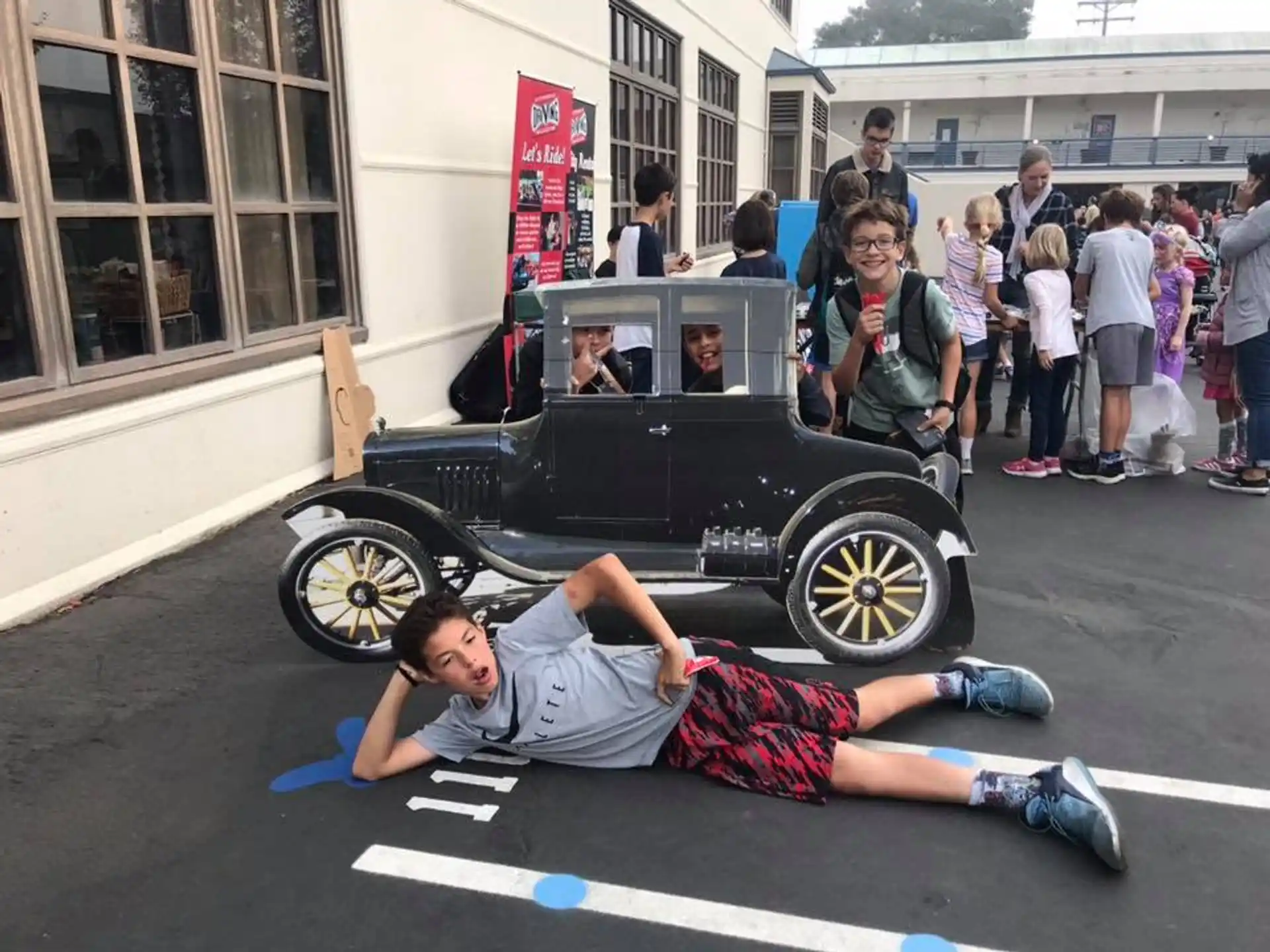 a man lying on the ground next to a car with people in the back