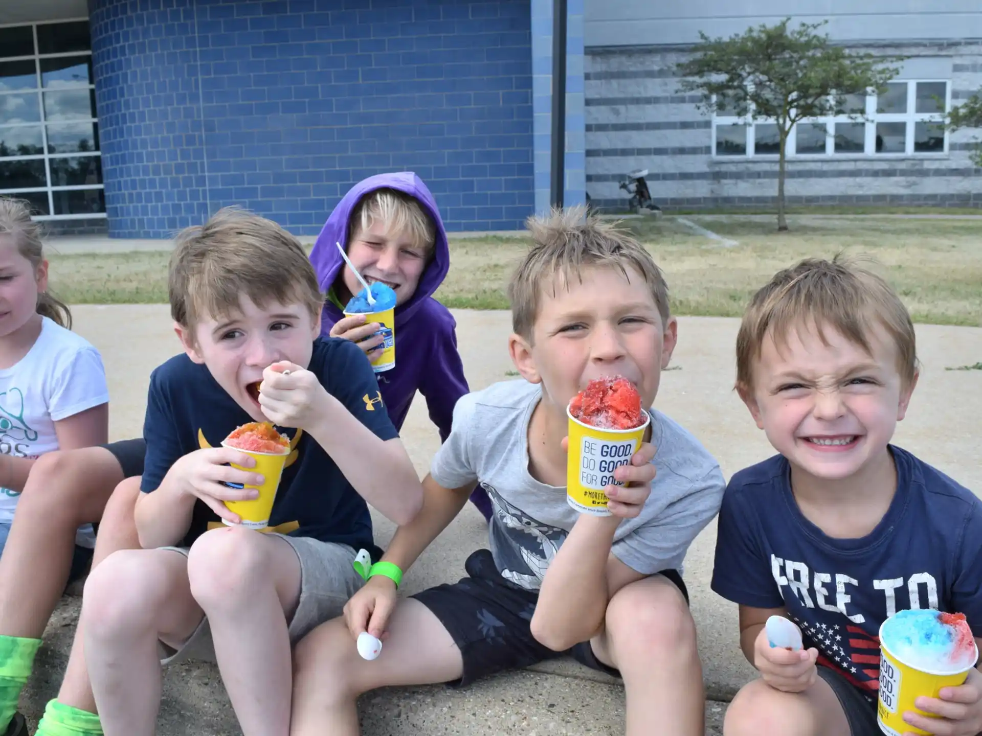 a group of kids sitting on the ground eating ice cream