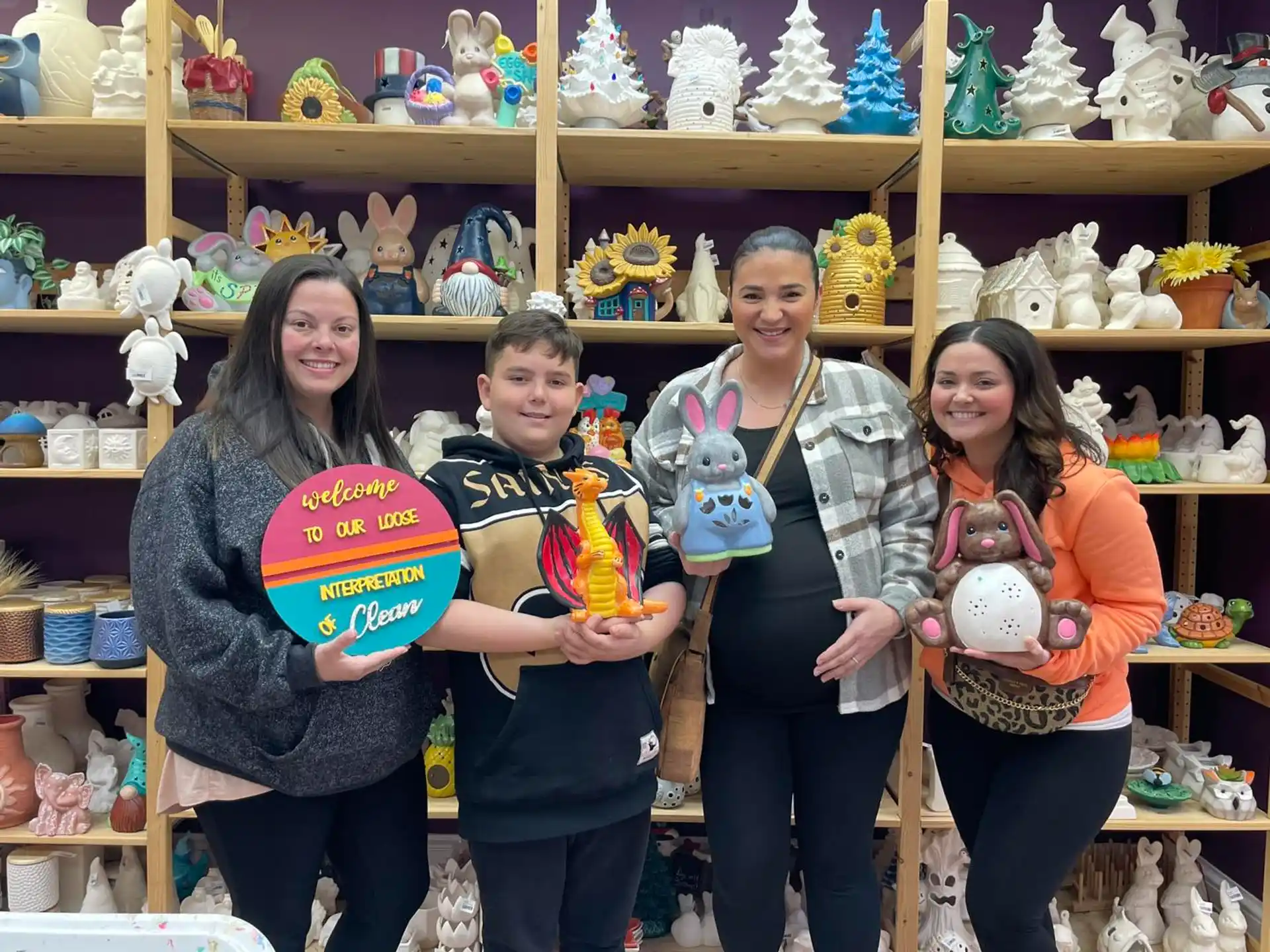 a group of people posing for a photo in front of a shelf of stuffed animals
