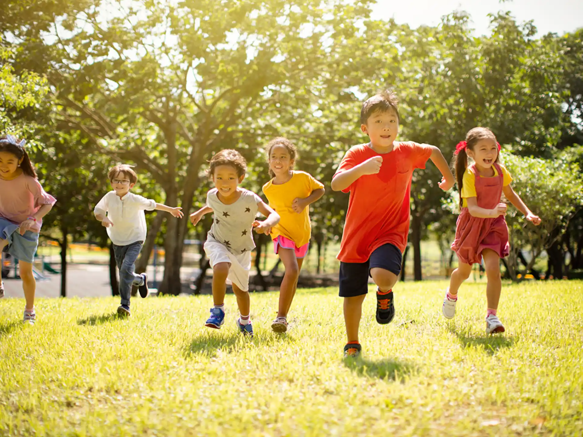 a group of children running on a grass field