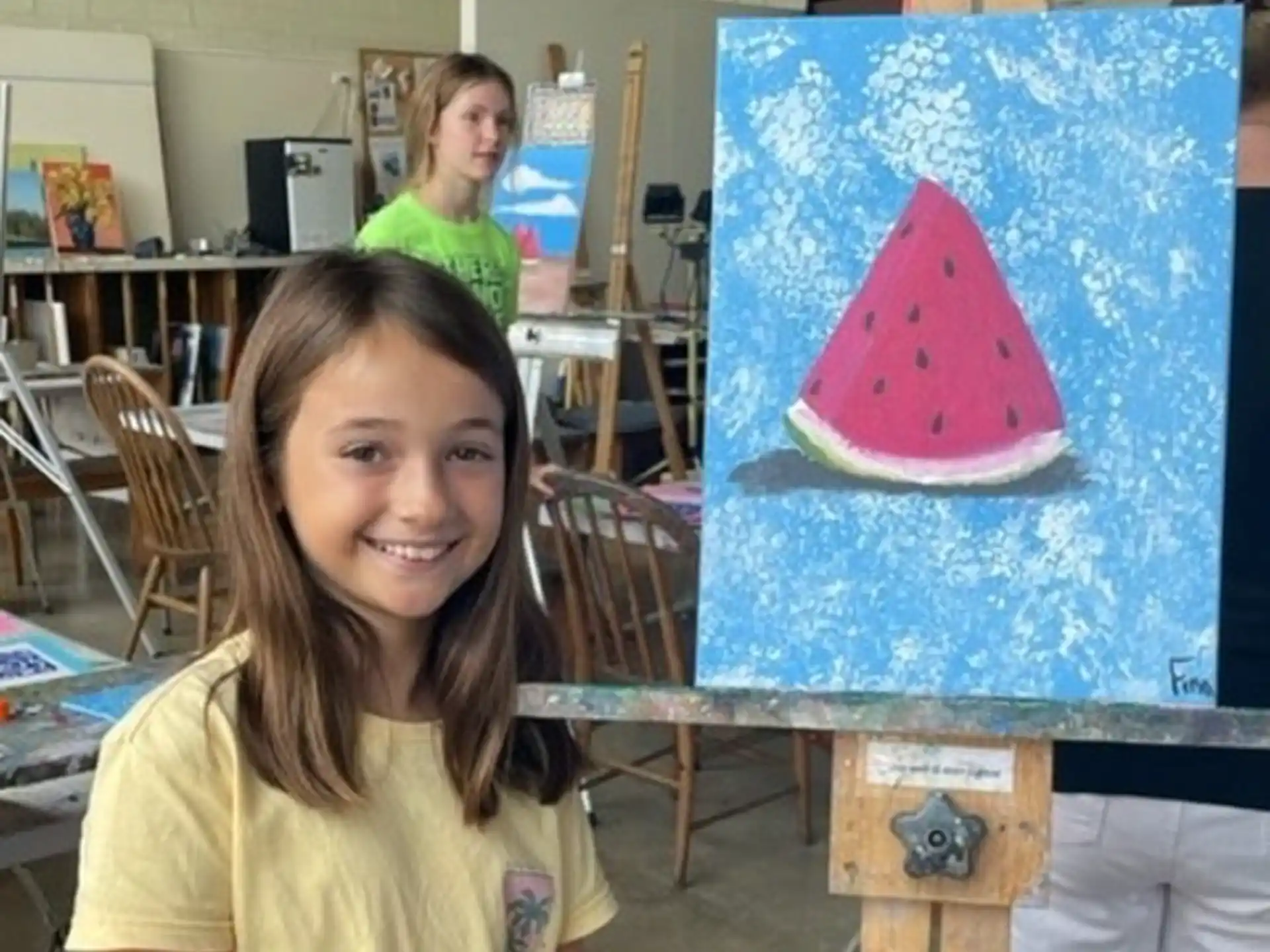a girl smiling next to a painting