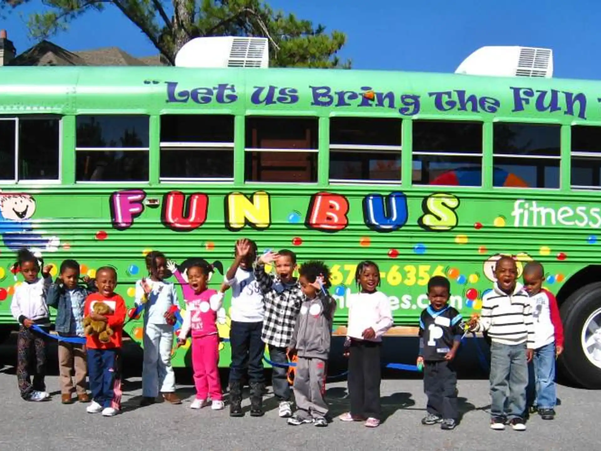 a group of children posing in front of a green bus