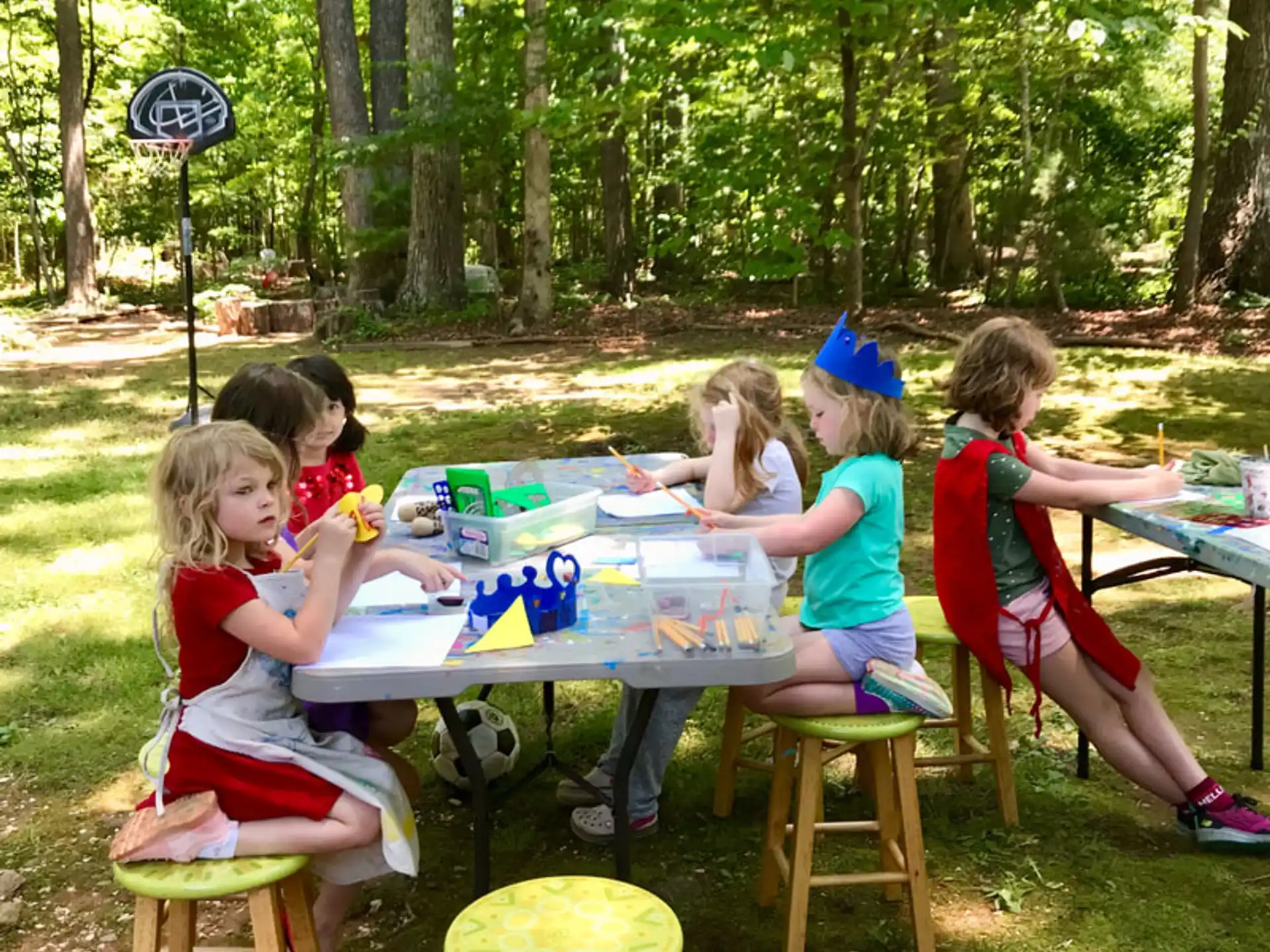 a group of children sitting around a table outside