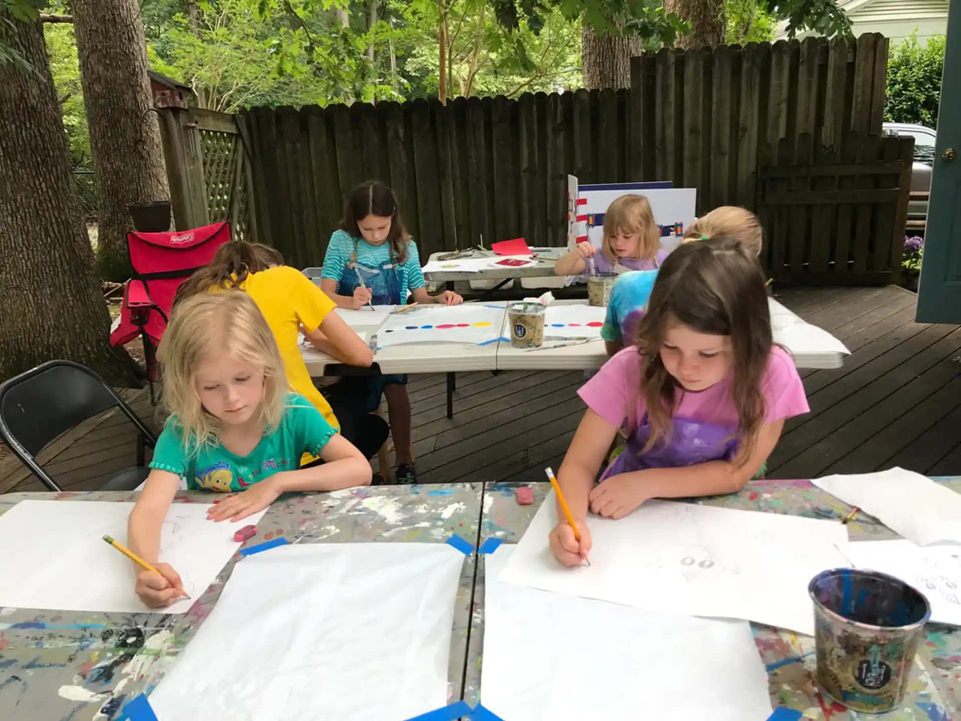 a group of children sitting at a table outside