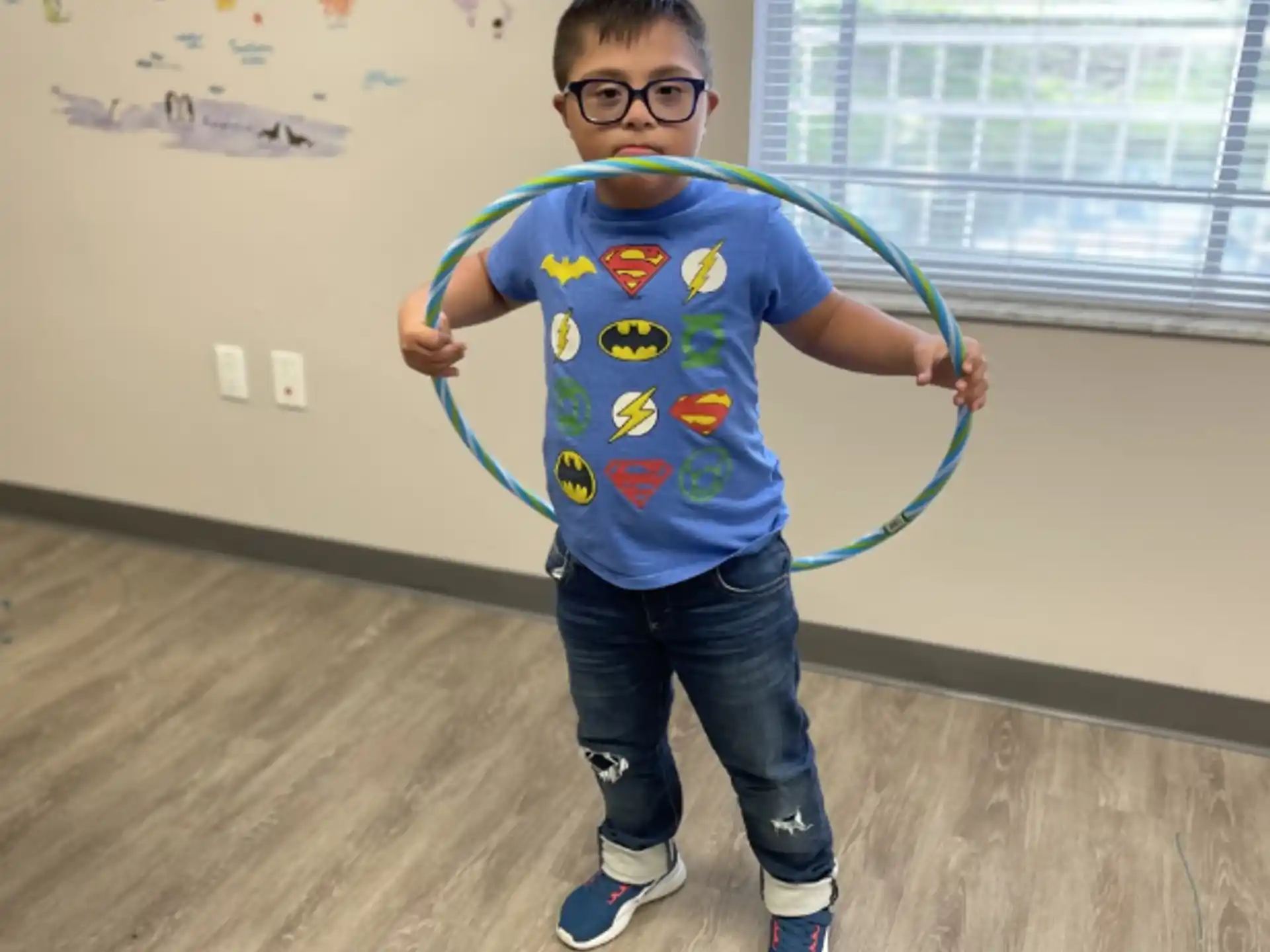 a boy wearing a blue shirt and holding a blue hoop in a room