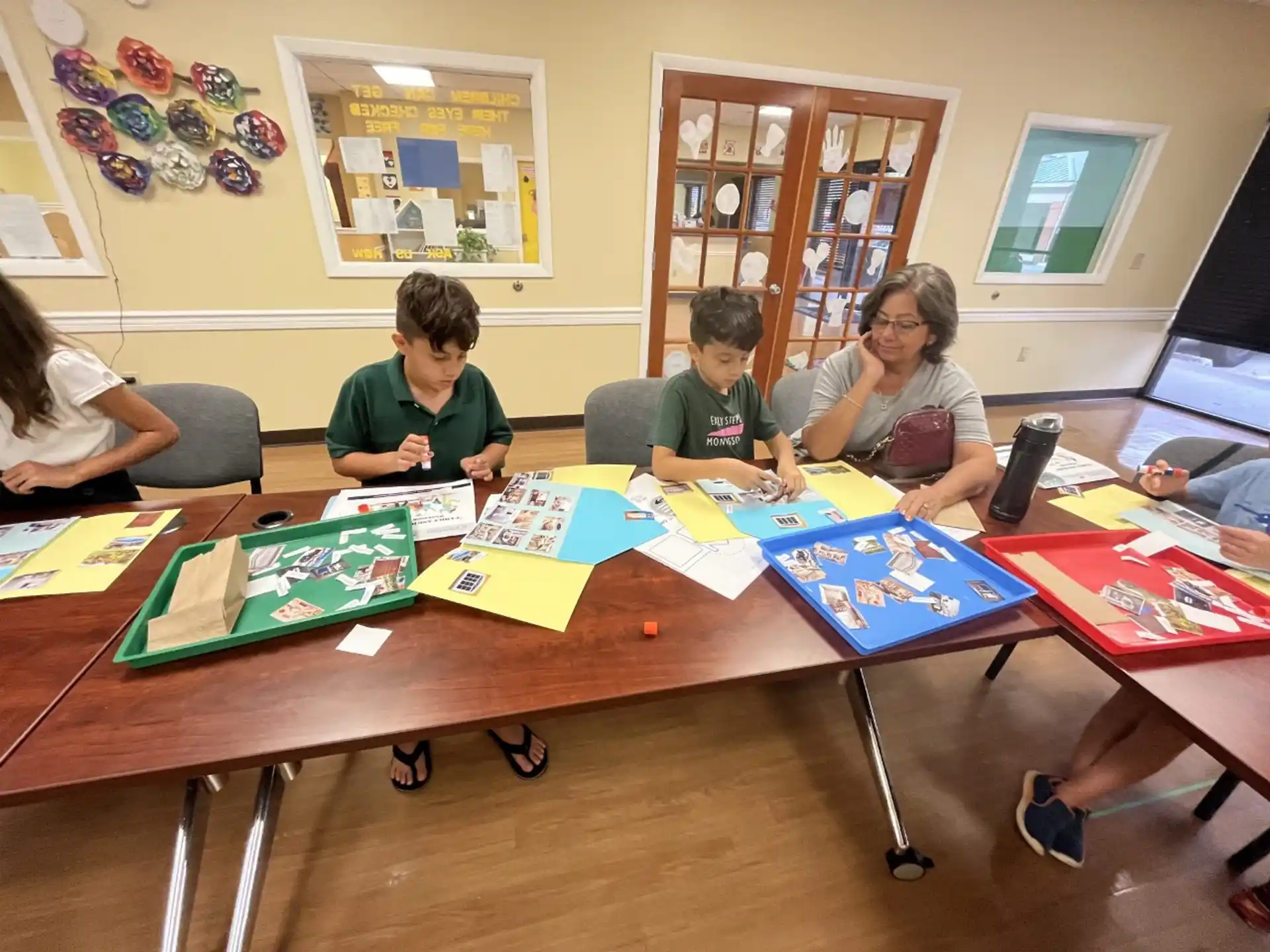 a group of people sitting at a table with colorful paper on it