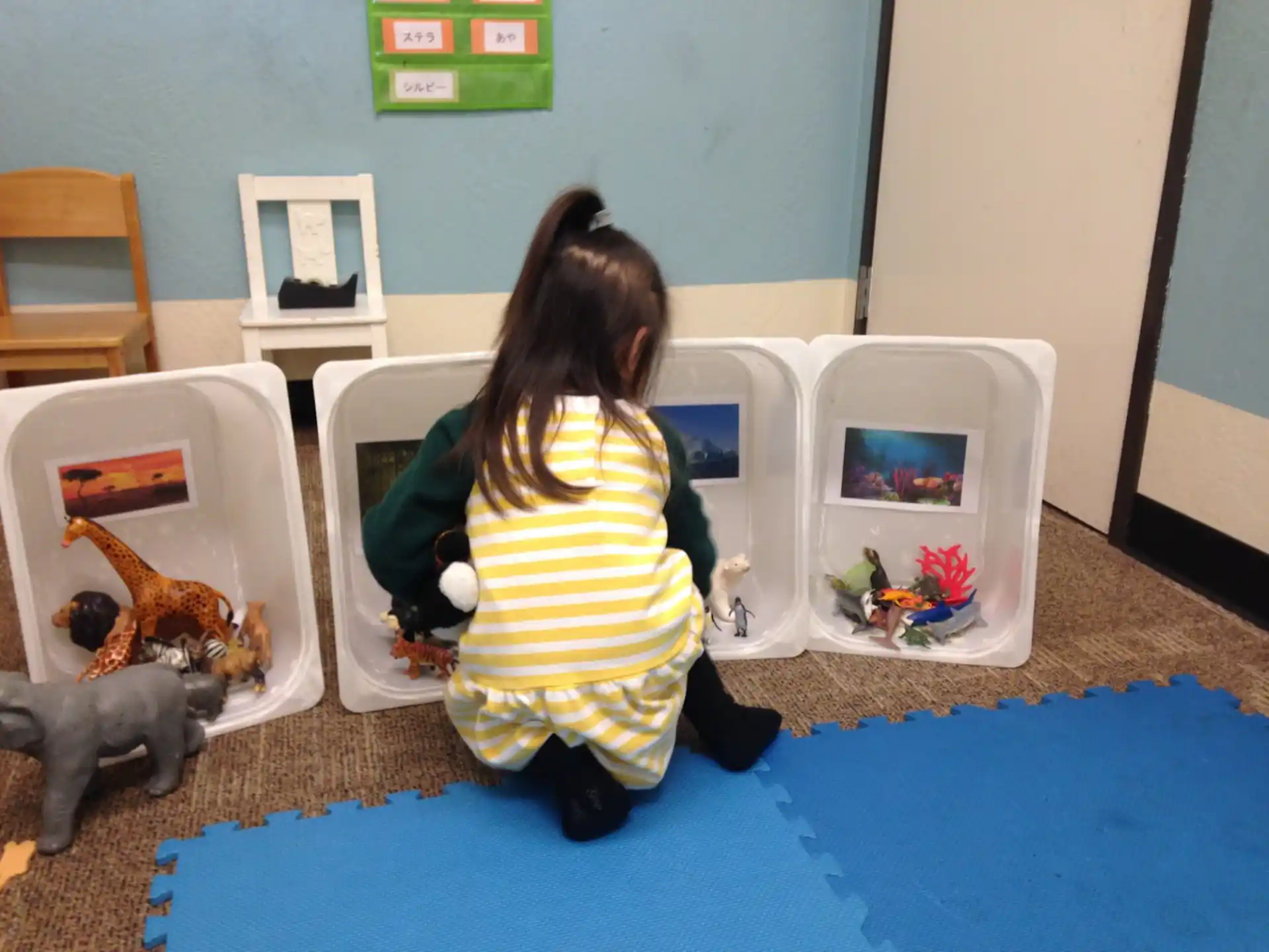 a girl sitting on the floor next to a doll house